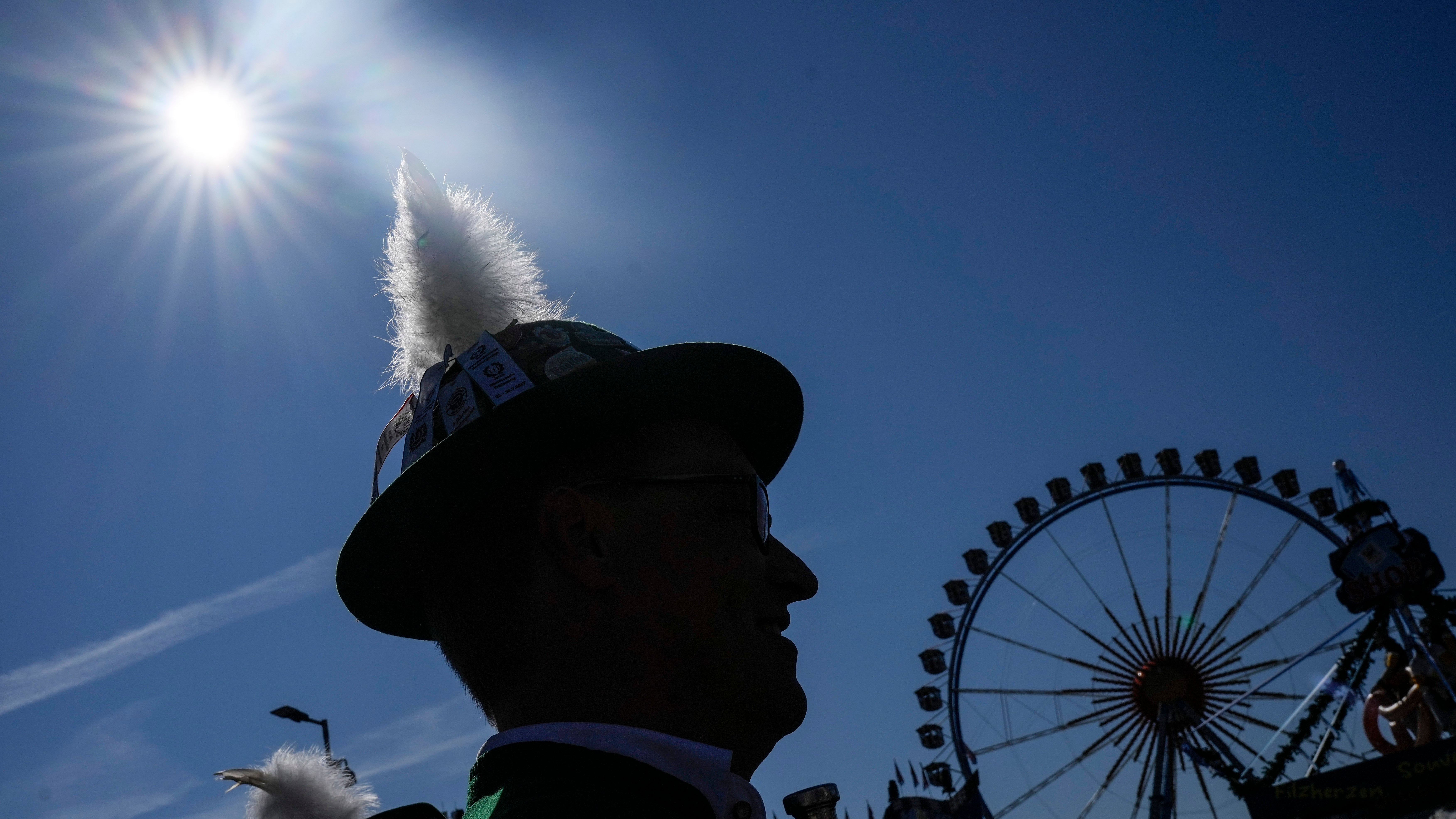 M&uuml;nchen, Samstag, 21. September 2024: Ein Mann mit einem traditionellen bayerischen Hut steht in der Sonne zu Beginn des 189. Oktoberfestes vor Bildern mit M&uuml;nchner Wahrzeichen (AP Photo/Matthias Schrader)
