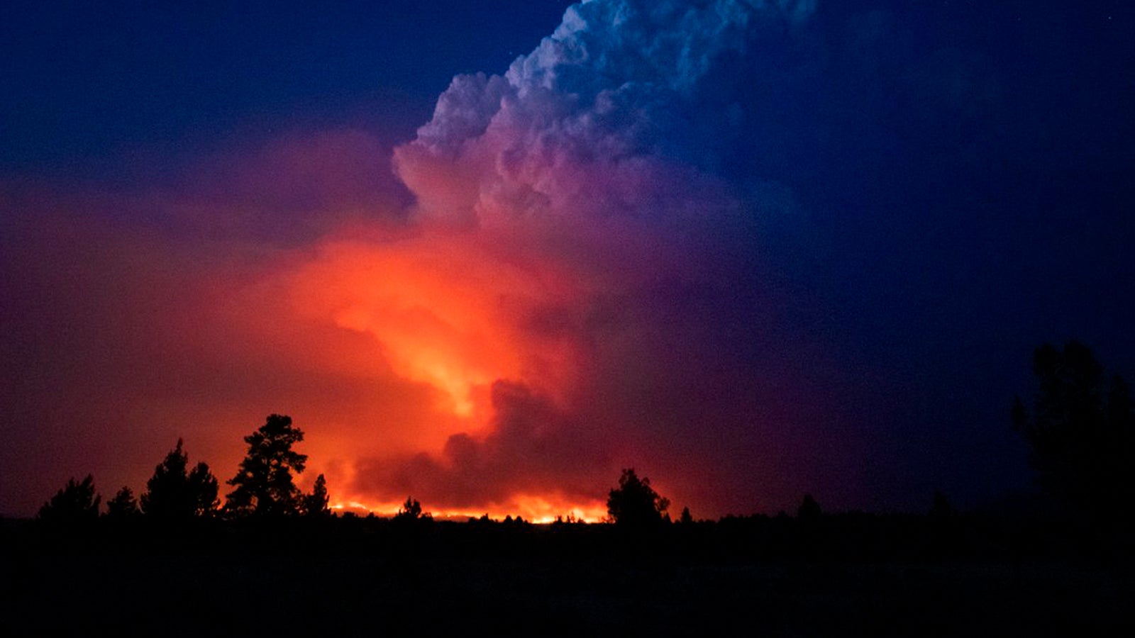 In this photo provided by the Oregon Office of State Fire Marshall, flames and smoke rise from the Bootleg fire in southern Oregon on Wednesday, July 14, 2021. The largest fire in the U.S. on Wednesday was burning in southern Oregon, to the northeast of the wildfire that ravaged a tribal community less than a year ago. The lightning-caused Bootleg fire was encroaching on the traditional territory of the Klamath Tribes, which still have treaty rights to hunt and fish on the land, and sending huge, churning plumes of smoke into the sky visible for miles. (John Hendricks/Oregon Office of State Fire Marshal via AP)