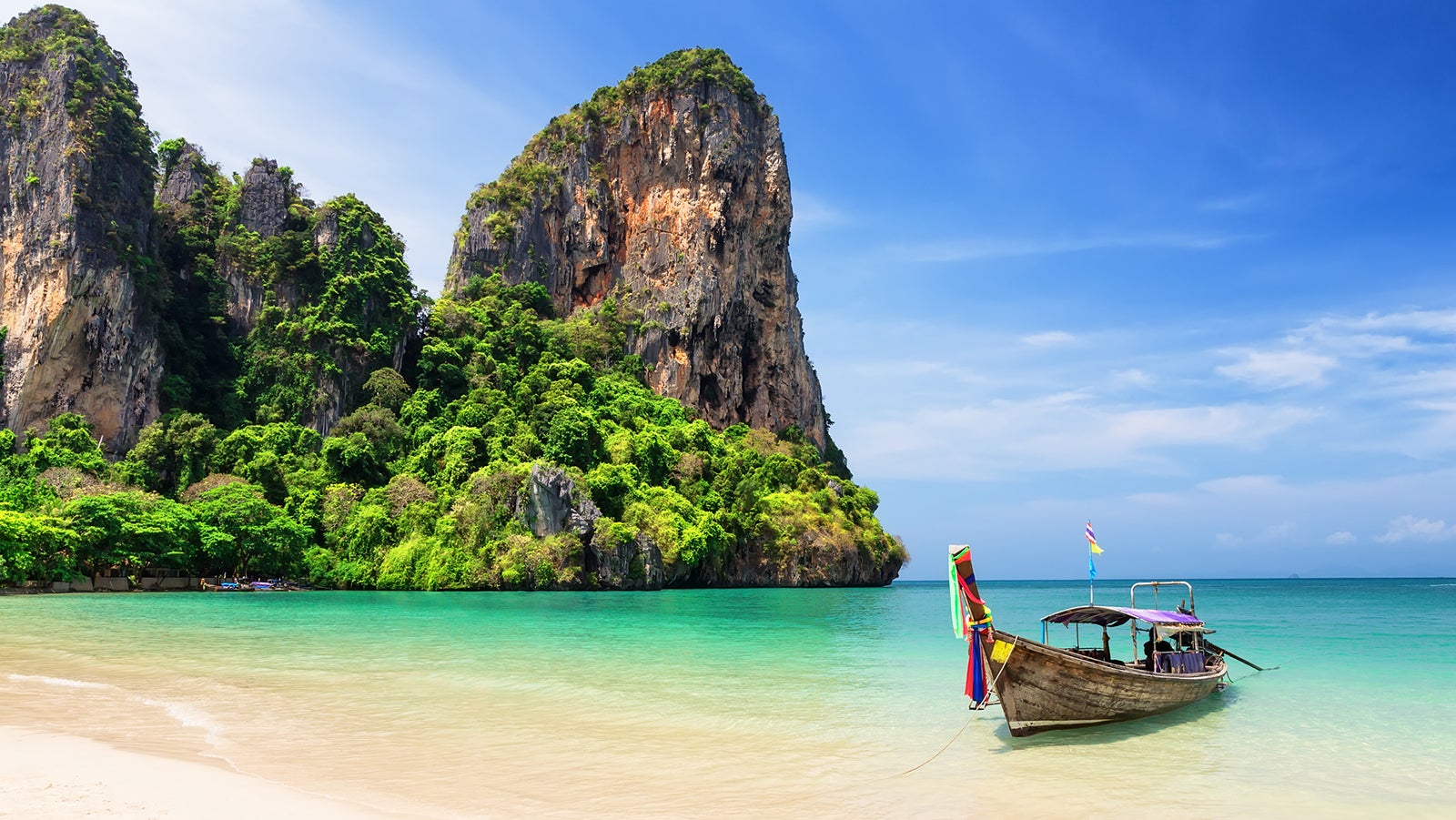 Thai traditional wooden longtail boat and beautiful sand Railay Beach in Krabi province. Ao Nang, Thailand.