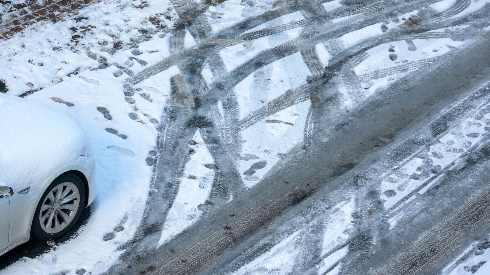 30.01.2021, Hamburg: Auto- und Fu&szlig;spuren im Schnee auf einer Stra&szlig;e. Das sonnig-winterliche Wetter hat am Samstag viele Familien zum Rodeln in die Hamburger Parks gelockt. Foto: Jonas Walzberg/dpa