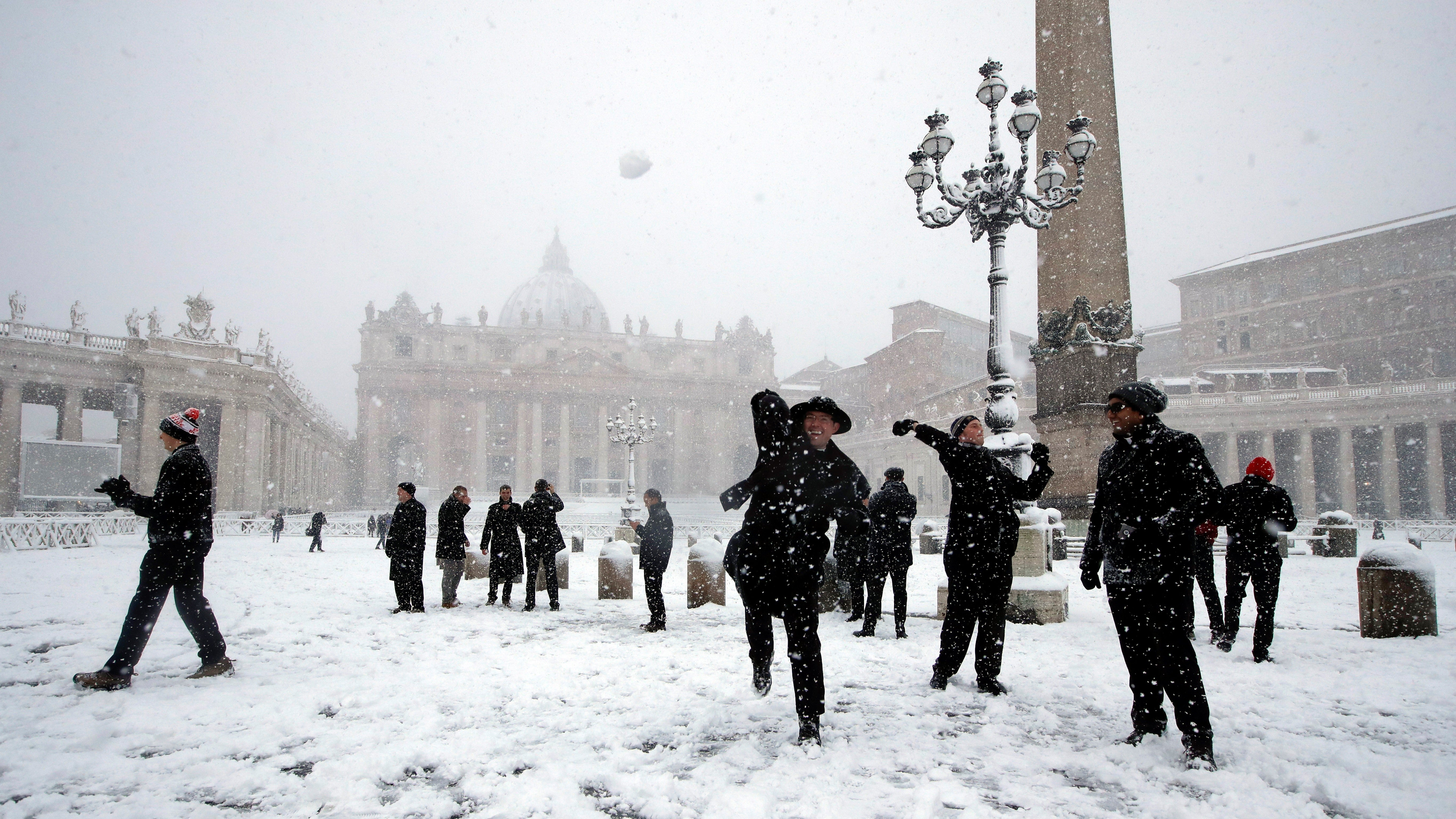 26.02.2018, Vatikan: Shawn Roser (M) aus Venice, Florida, der in Rom studiert, wirft einen Schneeball auf dem verschneiten Petersplatz. Ein K&auml;ltetief mit Schnee, Regen und starkem Wind hat Italien erreicht. Foto: Alessandra Tarantino/AP/dpa +++ dpa-Bildfunk +++