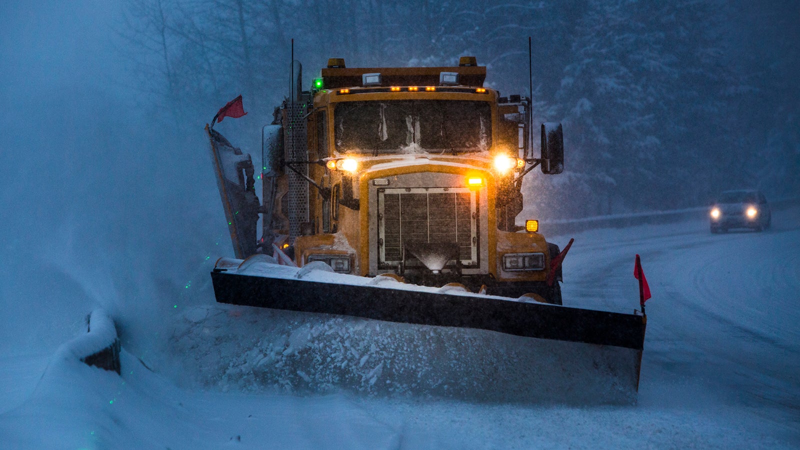 Truck plowing snow off the road at night.