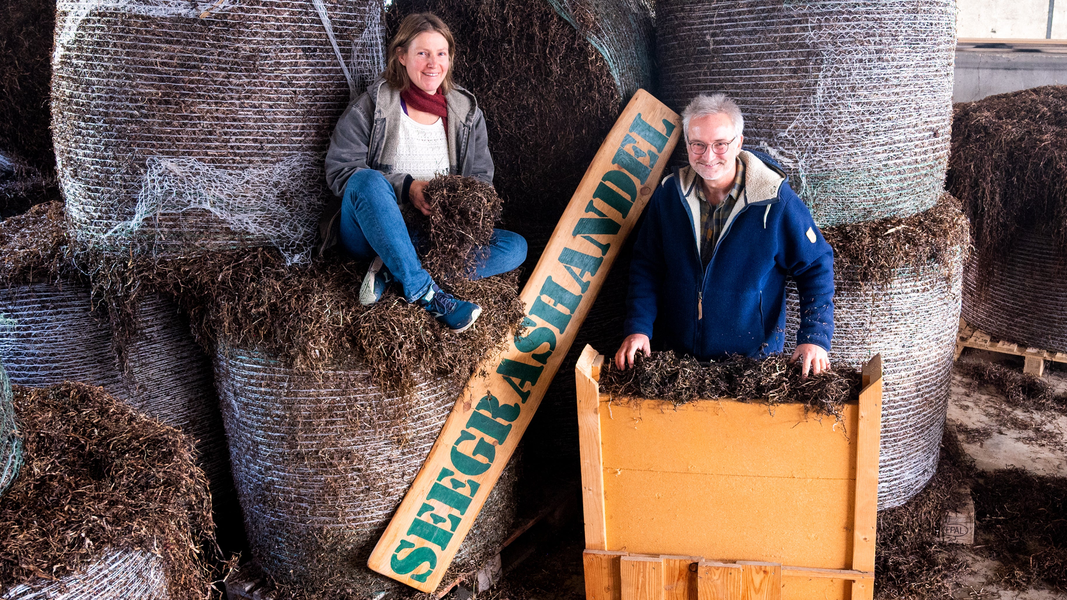 14.11.2023, Scheswig-Holstein, Westerau: Swantje Streich und J&ouml;rn Hartje, Seegrash&auml;ndler, sitzen und stehen in ihrem Lager auf und an Ballen mit Seegras. (Daniel Bockwoldt/dpa)


