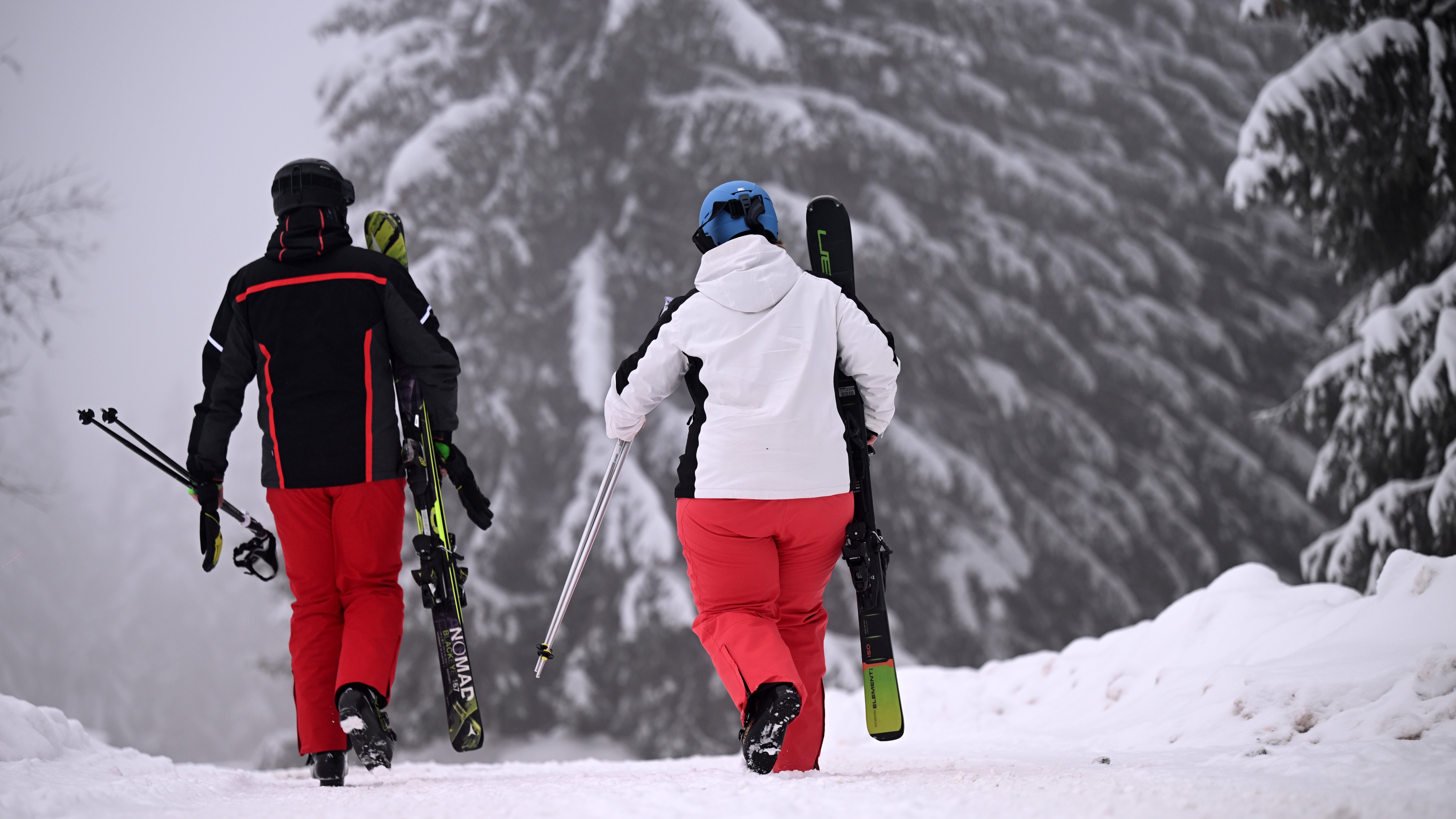 01.12.2023, Th&uuml;ringen, Oberhof: Skifahrer laufen zum Skilift am Fallbachhang in Oberhof, wo Anf&auml;nger in Kursen auch Skilaufen lernen k&ouml;nnen. (Martin Schutt/dpa)