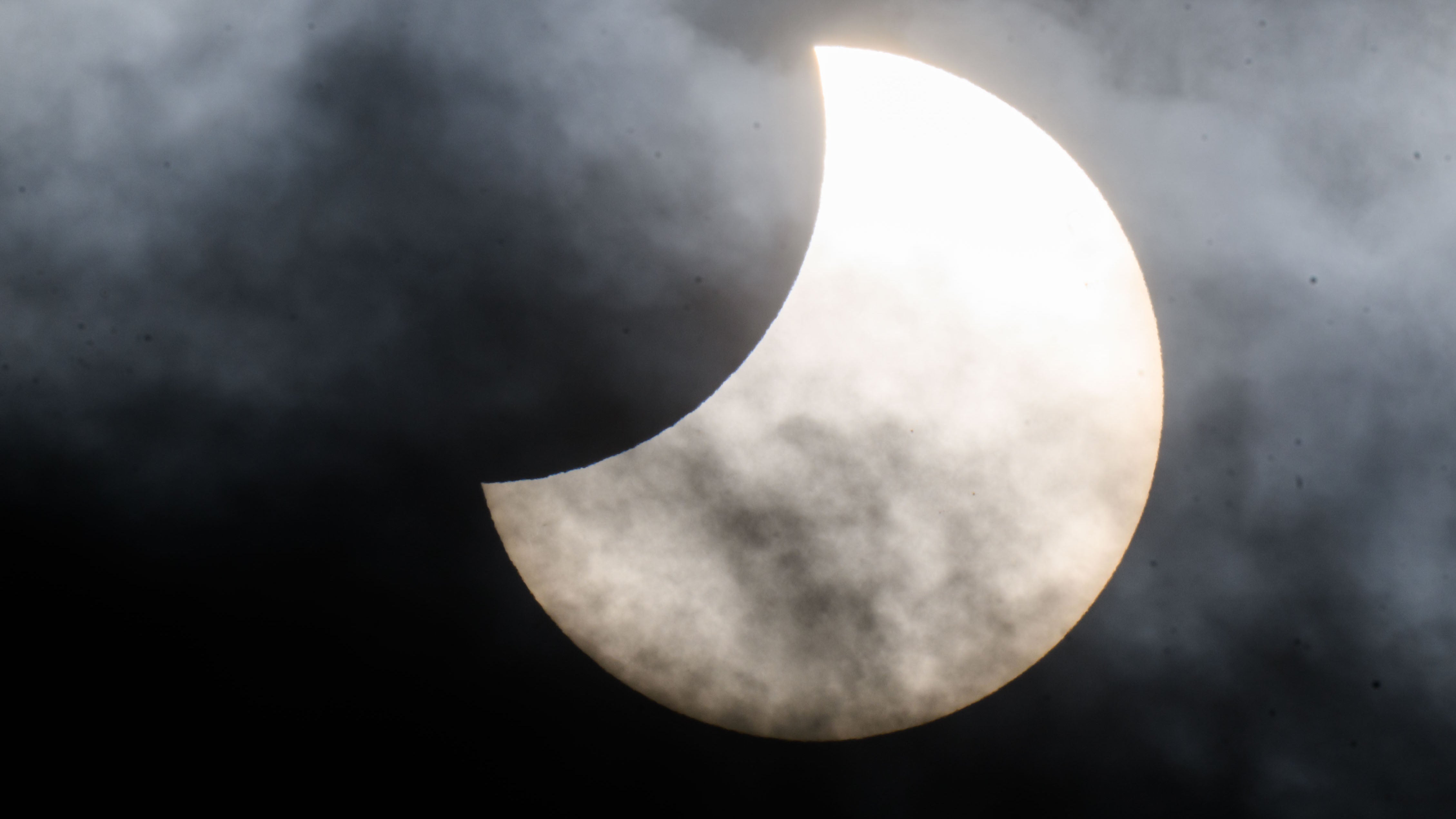 25.10.2022, Niedersachsen, Laatzen: Eine partielle Sonnenfinsternis ist zwischen Wolken am Himmel &uuml;ber der Region Hannover zu sehen. (Julian Stratenschulte/dpa)


