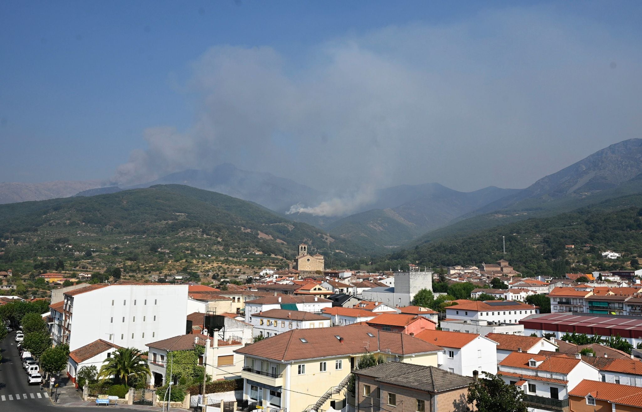 20.08.2025, Spanien, Hervas: Blick &uuml;ber den Ort auf die Waldbr&auml;nde in den Bergen. Speziell ausgebildete Einsatzkr&auml;fte der Feuerwehr sind aus Deutschland angereist, um bei der Bek&auml;mpfung der schlimmsten Wald- und Vegetationsbr&auml;nde seit Jahrzehnten zu helfen. (Sven K&auml;uler/dpa)