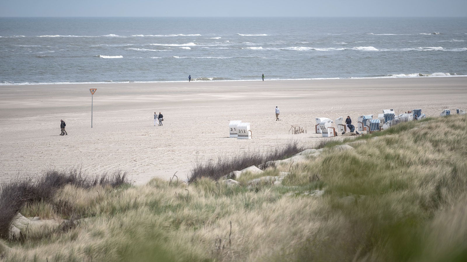 16.05.2020, Niedersachsen, Spiekeroog: Spazierg?nger laufen ?ber den Strand. Zahlreiche Menschen haben die Tourismus-Lockerungen diese Woche genutzt und sind zum Urlaub auf die Ostfriesischen Inseln gefahren. Foto: Sina Schuldt/dpa +++ dpa-Bildfunk +++
