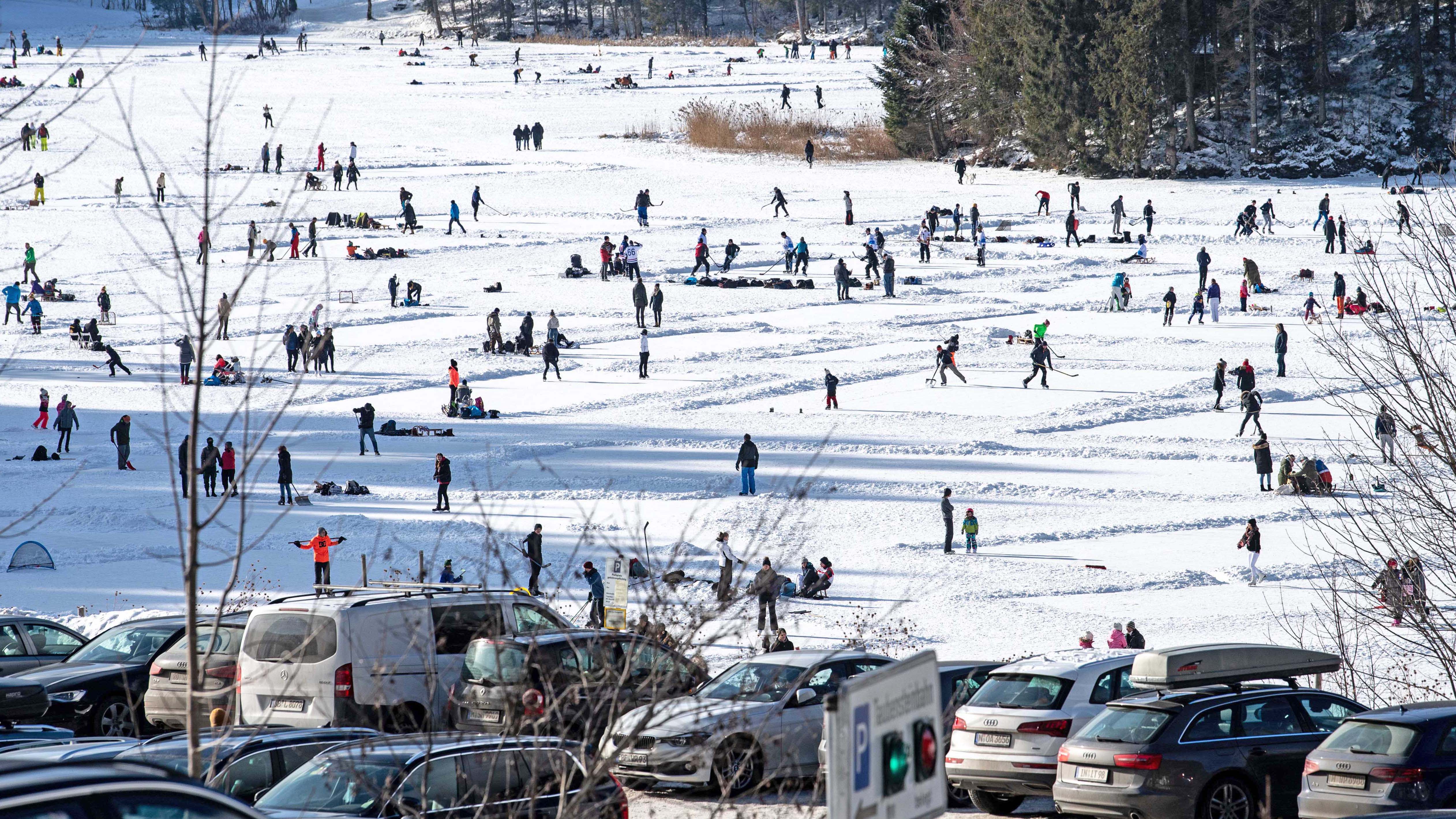 dpatopbilder - 09.01.2021, Bayern, Spitzingsee: Parkende Autos von Ausfl&uuml;glern sind vor dem zugefrorenen Spitzingsee zu sehen, auf dem sich zahlreiche Touristen und Einheimische tummeln. Ab dem 11.01.2020 gelten f&uuml;r touristische Ausfl&uuml;ge wegen der Corona-Pandemie strengere Regeln. Foto: Matthias Balk/dpa +++ dpa-Bildfunk +++