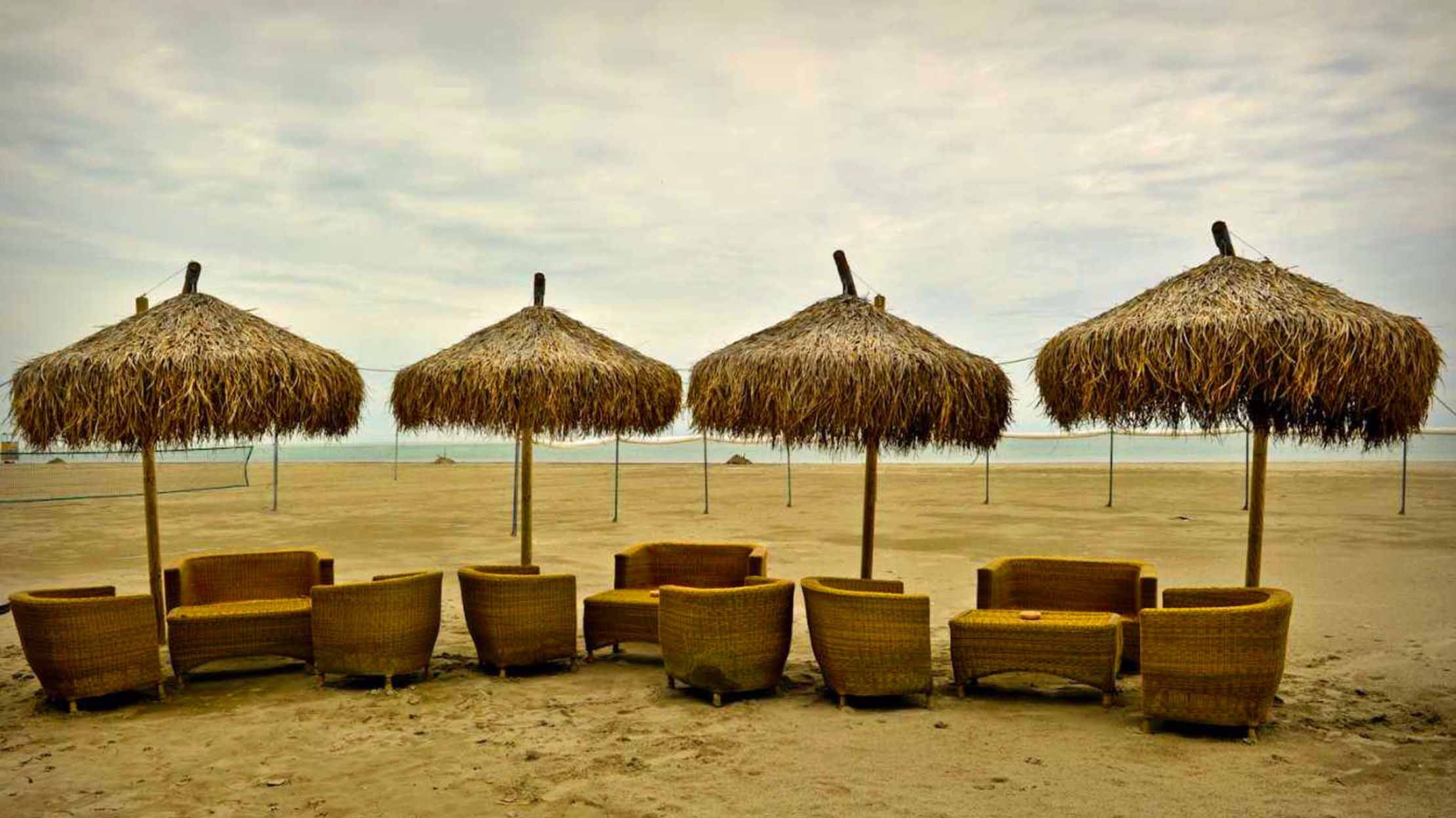 Four thatched umbrellas  in winter on the Marina Romea beach