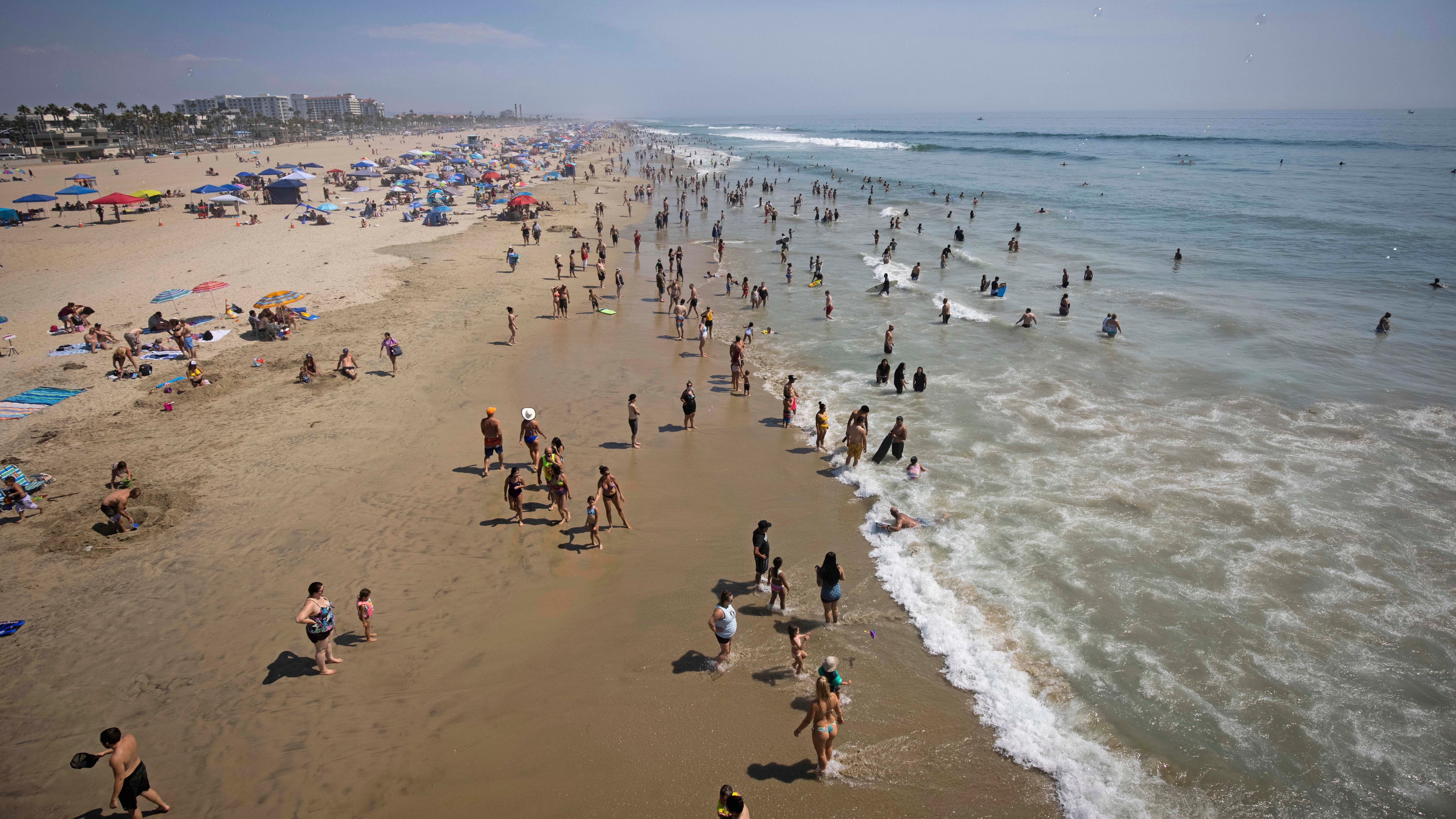 ARCHIV - 06.08.2020, USA, Huntington Beach: Menschen verbringen ihre Freizeit am Strand. Der Meeresspiegel k&circ;nnte Prognosen von US-Beh&circ;rden zufolge in den kommenden drei Jahrzehnten so stark steigen wie in den vergangenen 100 Jahren. (zu dpa &acute;Meeresspiegelanstieg an US-K&cedil;sten: 30 Zentimeter in drei Jahrzehnten&ordf;) Foto: Christian Monterrosa/AP/dpa +++ dpa-Bildfunk +++