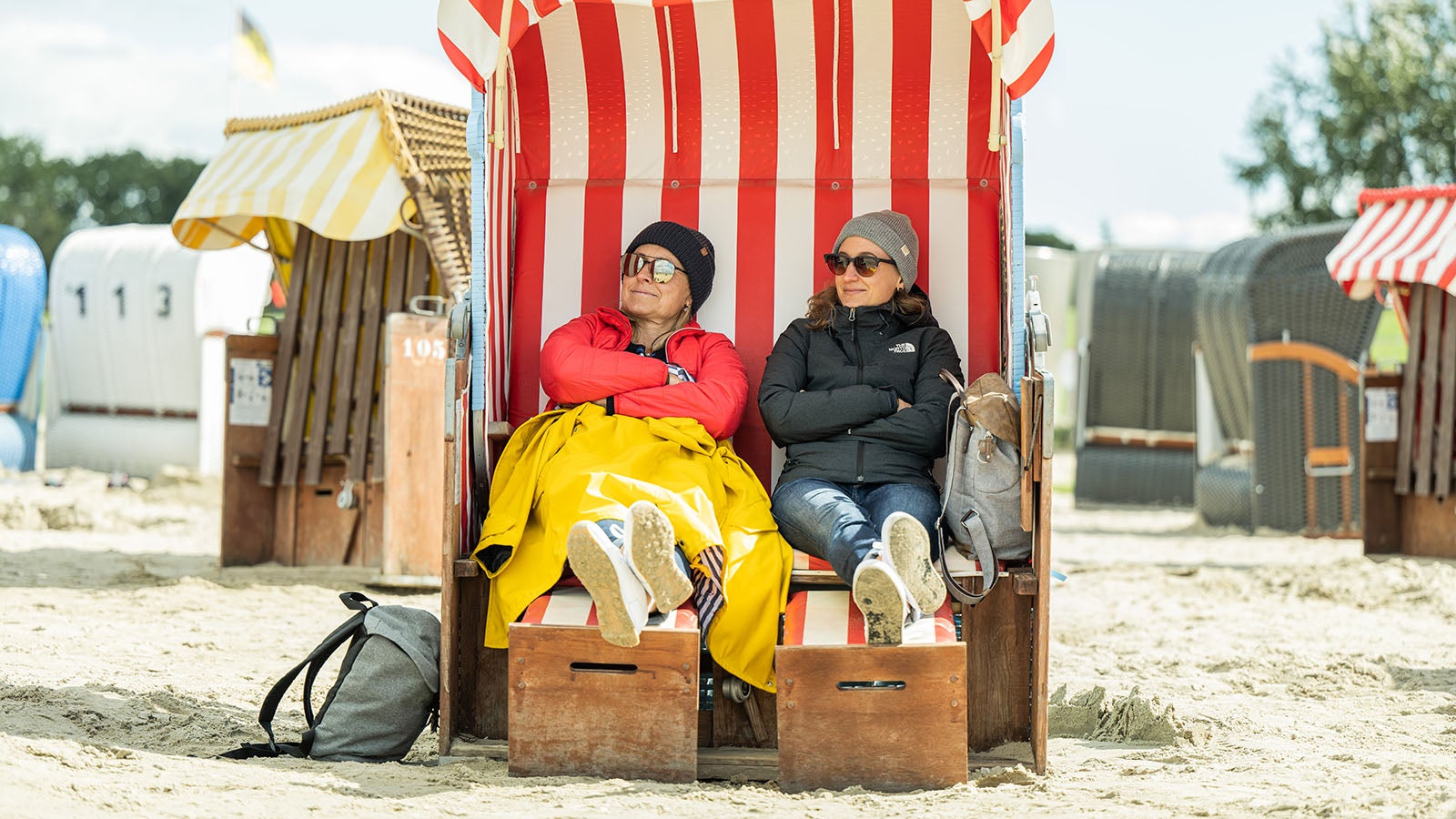 26.08.2021, Niedersachsen, Dangast: Die Urlauberinnen Claudia (l) und Julia aus Baden W&uuml;rttemberg sitzen in einem Strandkorb am Strand von Dangast. Foto: Mohssen Assanimoghaddam/dpa +++ dpa-Bildfunk +++