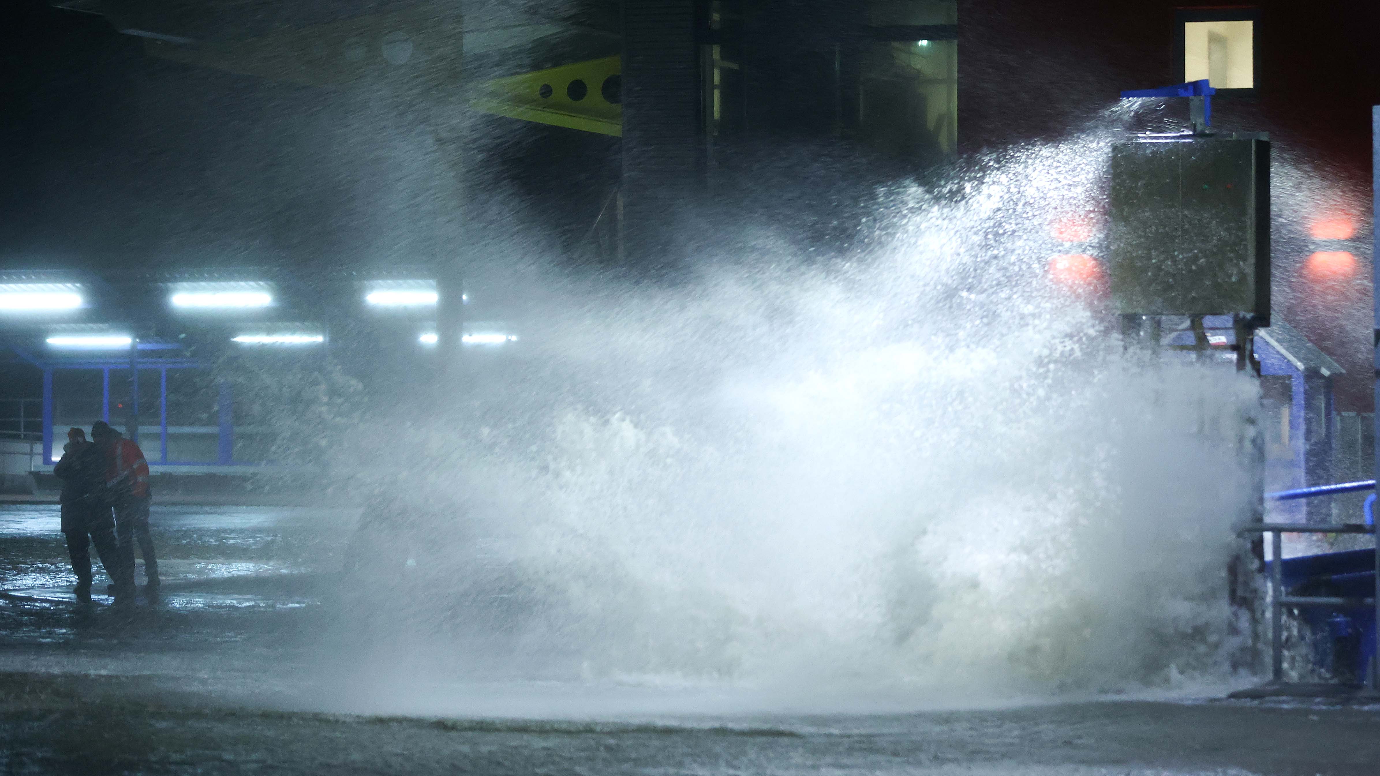 29.01.2022, Schleswig-Holstein, Dageb&cedil;ll: Passanten sind neben der Gischt der aufgepeitschten Nordsee am &cedil;berfluteten F&permil;hranleger Dageb&cedil;ll unterwegs. Der Deutsche Wetterdienst DWD warnte vor Sturm am Wochenende durch das Sturmtief &acute;Nadia&ordf;. Foto: Bodo Marks//dpa +++ dpa-Bildfunk +++