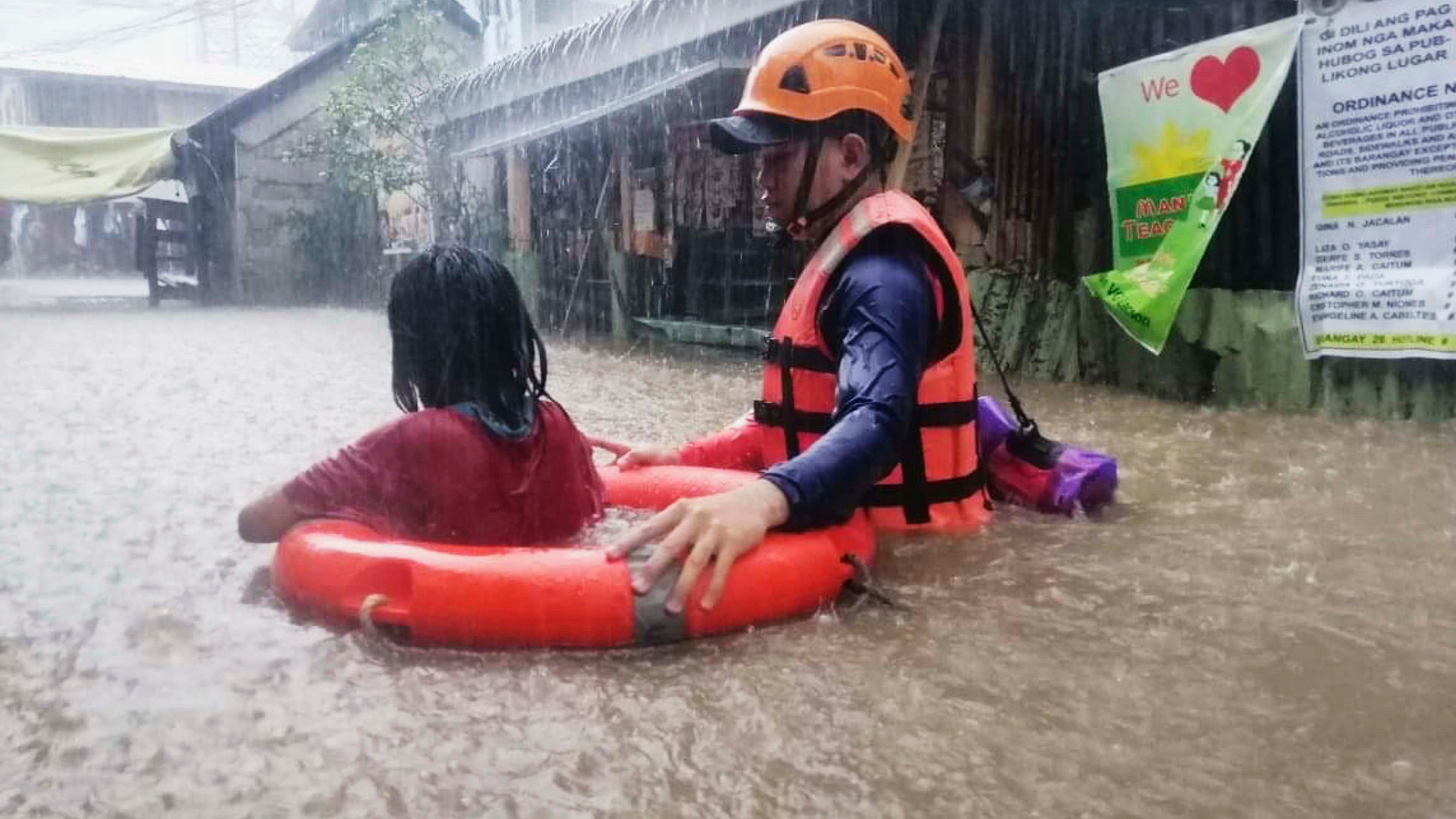 HANDOUT - 16.12.2021, Philippinen, Cagayan De Oro: Dieses von der philippinischen K&cedil;stenwache zur Verf&cedil;gung gestellte Foto zeigt eine Rettungskraft die ein M&permil;dchen durch das Hochwasser der &lsaquo;berschwemmungen nach starken Regenf&permil;llen ausgel&circ;st durch den Taifun Rai evakuiert. Foto: Uncredited/Philippine Coast Guard/dpa - ACHTUNG: Nur zur redaktionellen Verwendung und nur mit vollst&permil;ndiger Nennung des vorstehenden Credits +++ dpa-Bildfunk +++