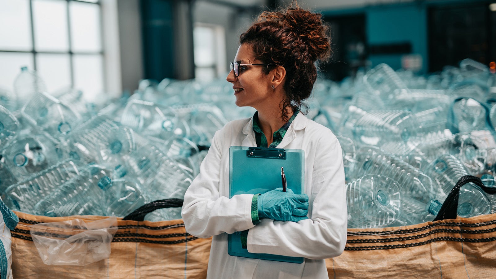 Young happy female worker in bottling factory recycling department. Inspection quality control.