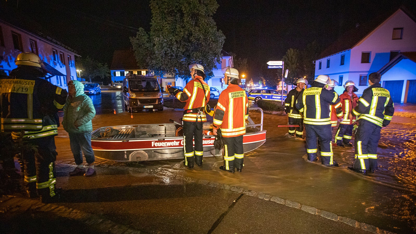 07.06.2021, Baden-W&uuml;rttemberg, Rot an der Rot: Feuerwehrleute stehen neben einem Feuerwehrboot auf einer Stra&szlig;e in den Fluten eines heftigen Unwetters. Ein&nbsp;Mann war bei&nbsp;den heftigen&nbsp;Regenf&auml;llen in seiner&nbsp;Wohnung im Untergeschoss eines&nbsp;Mehrfamilienhauses ertrunken.    (zu dpa "Mann wird in Wohnung von&nbsp;Wassermassen &uuml;berrascht und ertrinkt") Foto: Simon Adomat/VMD Images/dpa +++ dpa-Bildfunk +++