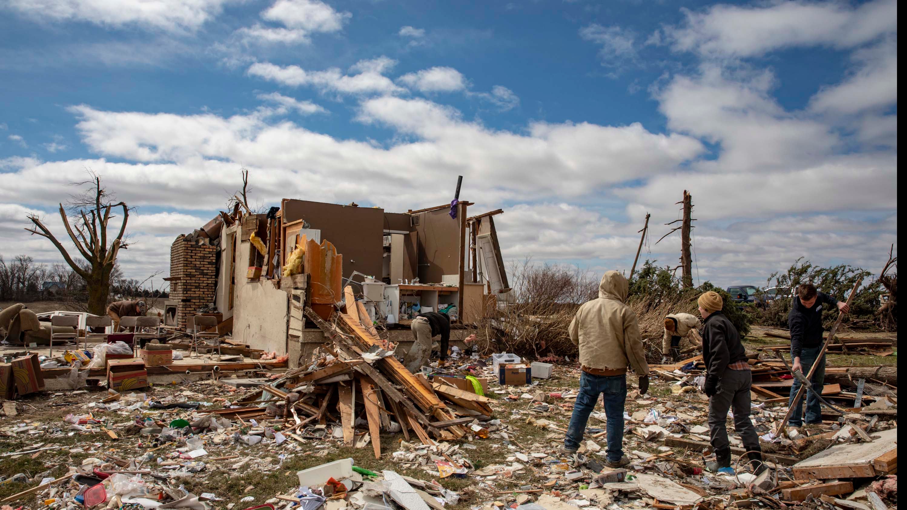 01.04.2023, USA, Wellman: Familienmitglieder und Nachbarn schauen sich auf der Farm von Ed Whestine s&uuml;dwestlich von Wellman die Tr&uuml;mmer an. Eine Serie von Tornados hat in den USA mehreren Menschen das Leben gekostet und schwere Sch&auml;den angerichtet. Foto: Nick Rohlman/The Gazette/AP/dpa - ACHTUNG: Nur zur redaktionellen Verwendung und nur mit vollst&auml;ndiger Nennung des vorstehenden Credits +++ dpa-Bildfunk +++