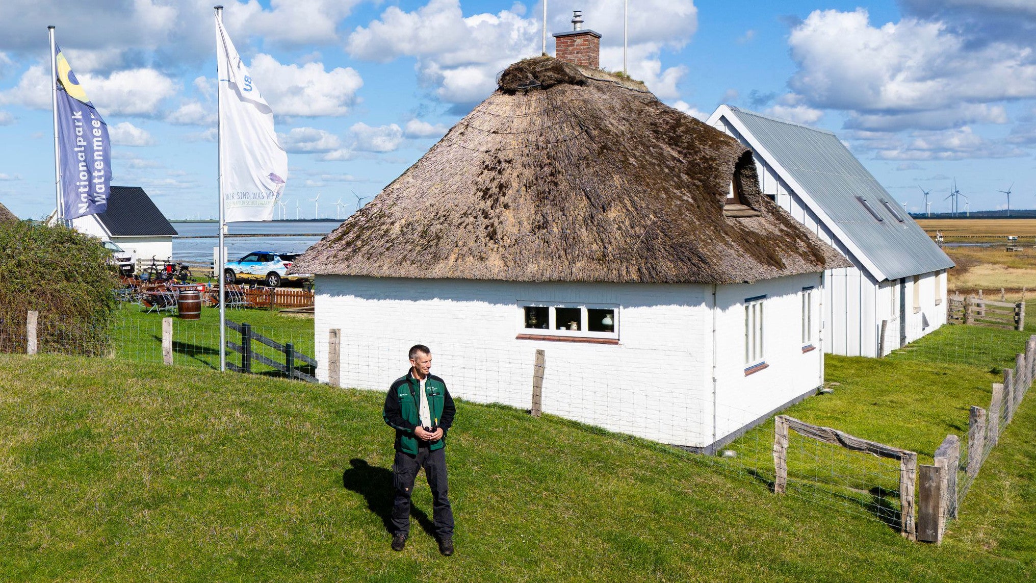 23.09.2025, Schleswig-Holstein, Reu&szlig;enk&ouml;ge: Rainer Rehm, Nationalpark-Ranger im Bereich Hamburger Hallig, steht auf der Warft (Luftaufnahme mit einer Drohne) (Frank Molter/dpa)