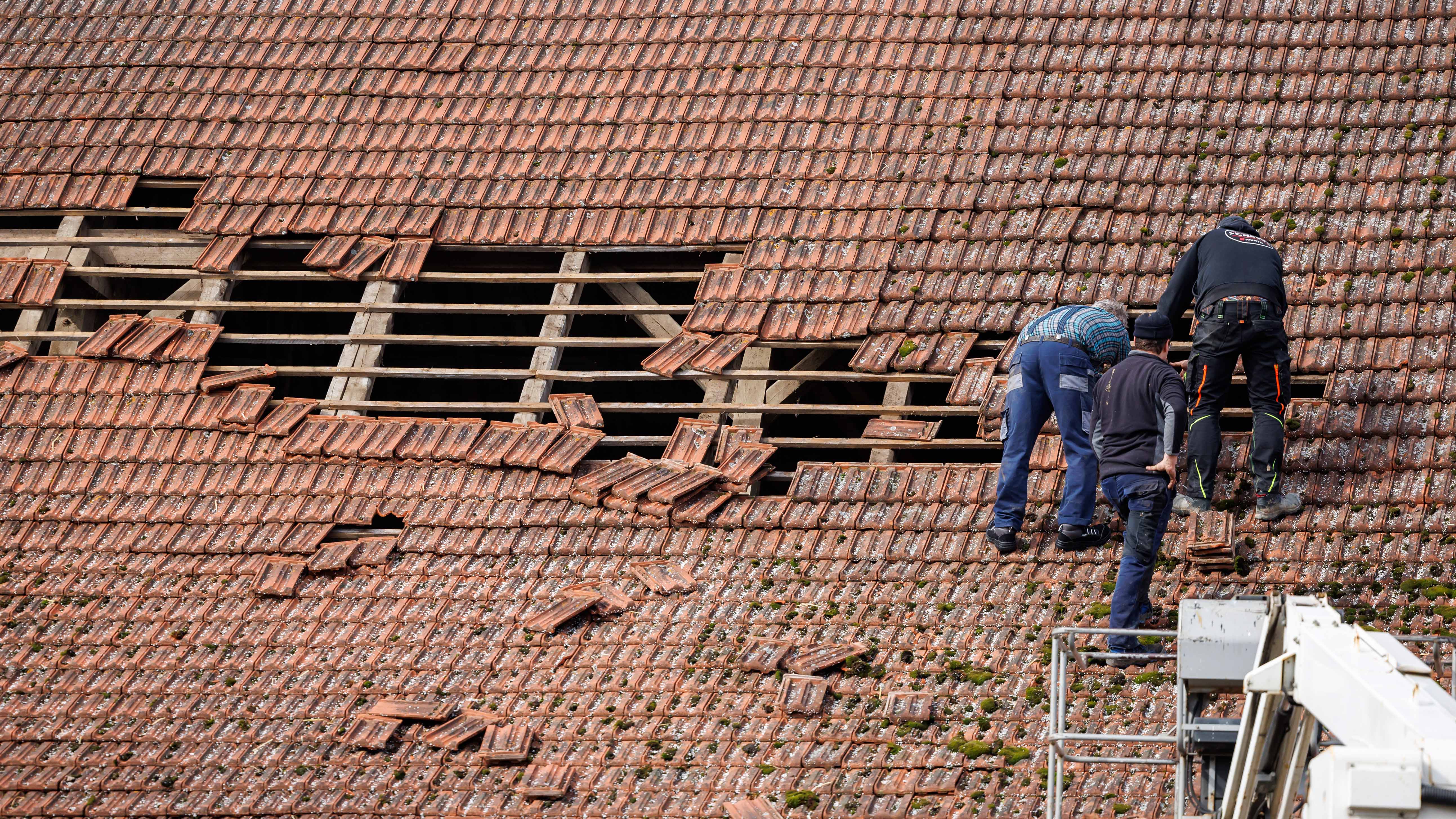 dpatopbilder - 05.04.2024, Bayern, Berching: Anwohner des Ortsteils Wackersberg reparieren ein durch starken Wind besch&permil;digtes Dach. Rund 30 Geb&permil;ude sind im Landkreis Neumarkt in der Oberpfalz durch Wetterauswirkungen besch&permil;digt worden. Etwa 20 landwirtschaftlich genutzte Geb&permil;ude und 10 Wohnh&permil;user, so ein Feuerwehrsprecher. Neben Dachsch&permil;den wurden demnach auch Fenster durch Dachziegel eingeschlagen und Garagentore herausgerissen. Foto: Daniel Karmann/dpa +++ dpa-Bildfunk +++