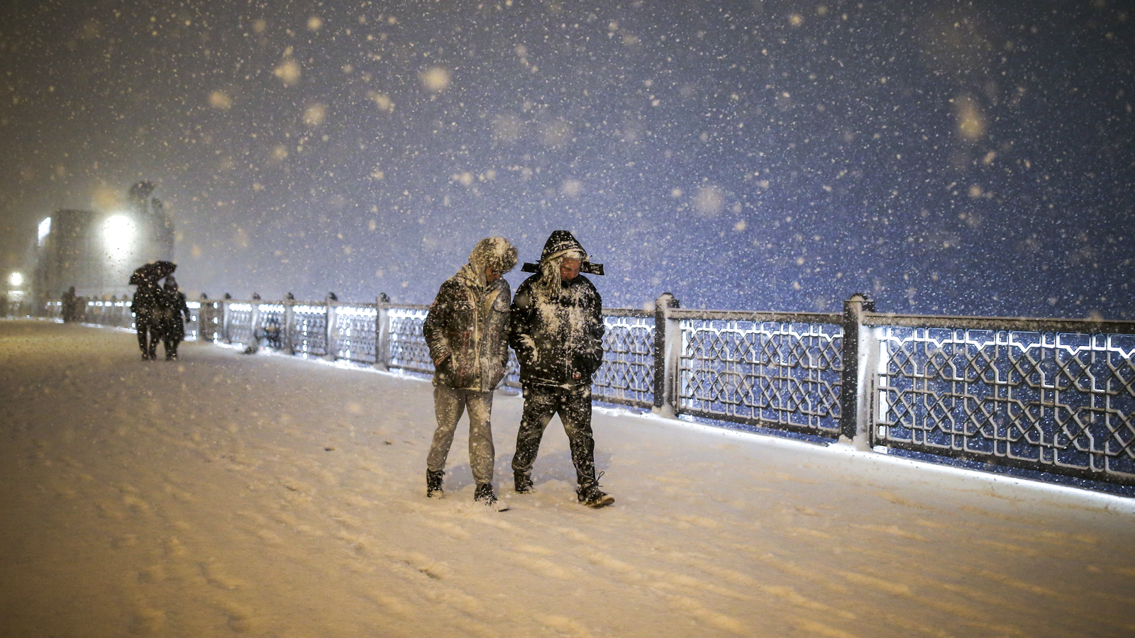 12.03.2022, T&uuml;rkei, Istanbul: Fu&szlig;g&auml;nger, die teilweise vom Schnee bedeckt sind, gehen bei Schneefall &uuml;ber die Galata-Br&uuml;cke. Der starke Schneefall hat den Flug-, Schiffs- und Landverkehr in Istanbul zum Erliegen gebracht und zu Schulschlie&szlig;ungen gef&uuml;hrt. Foto: Emrah Gurel/AP/dpa +++ dpa-Bildfunk