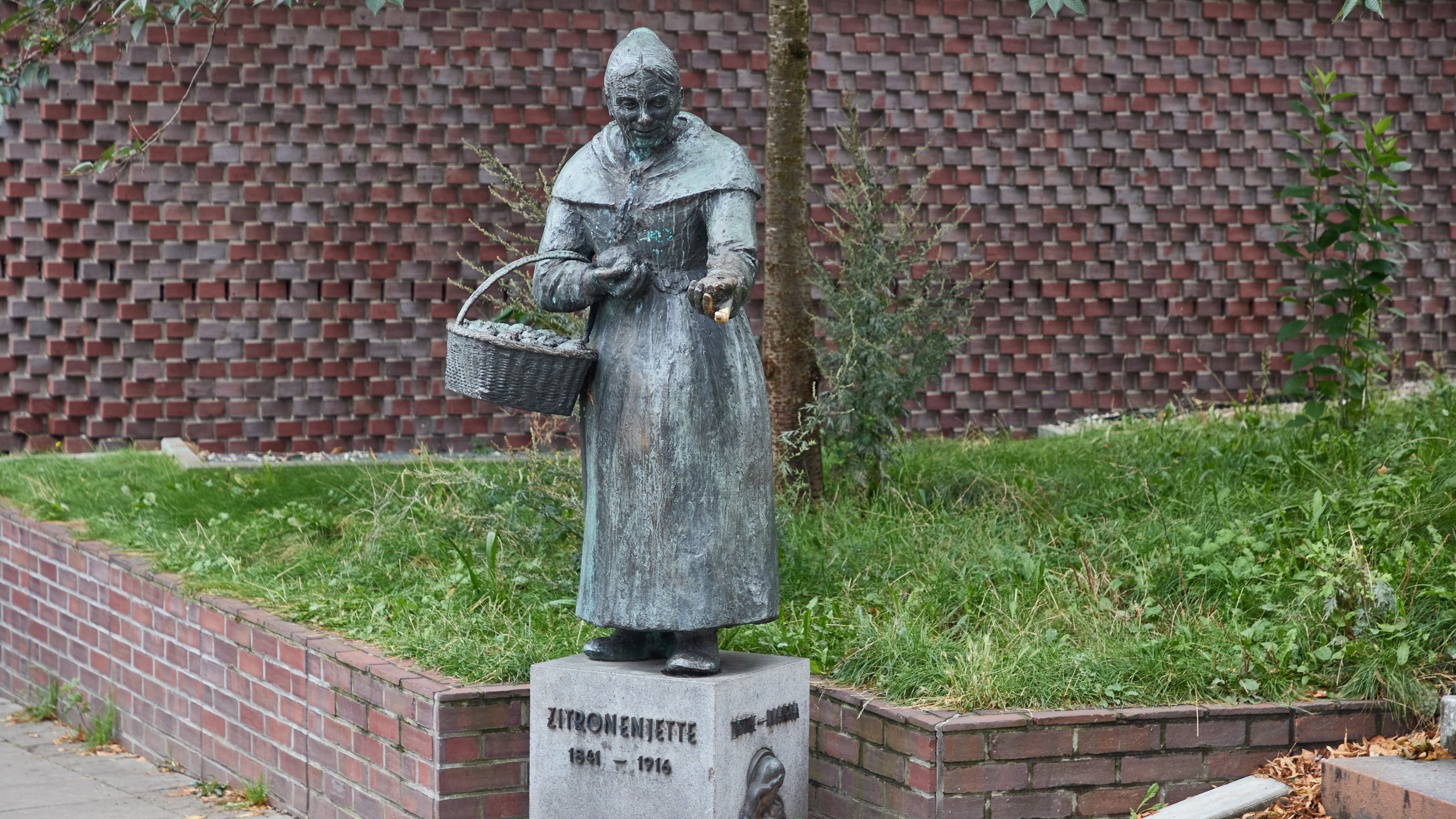 30.08.2024, Hamburg: Blick auf die Skulptur "Zitronenjette" an der Ludwig-Erhard-Stra&szlig;e. Henriette Johanne Marie M&uuml;ller, bekannt als "Zitronenjette", lebte im 19. Jahrhundert und erlangte in Hamburg Bekanntheit, weil sie dort jahrzehntelang tags&uuml;ber Zitronen in den Stra&szlig;en, Kneipen und Bars verkaufte. (Georg Wendt/dpa)
