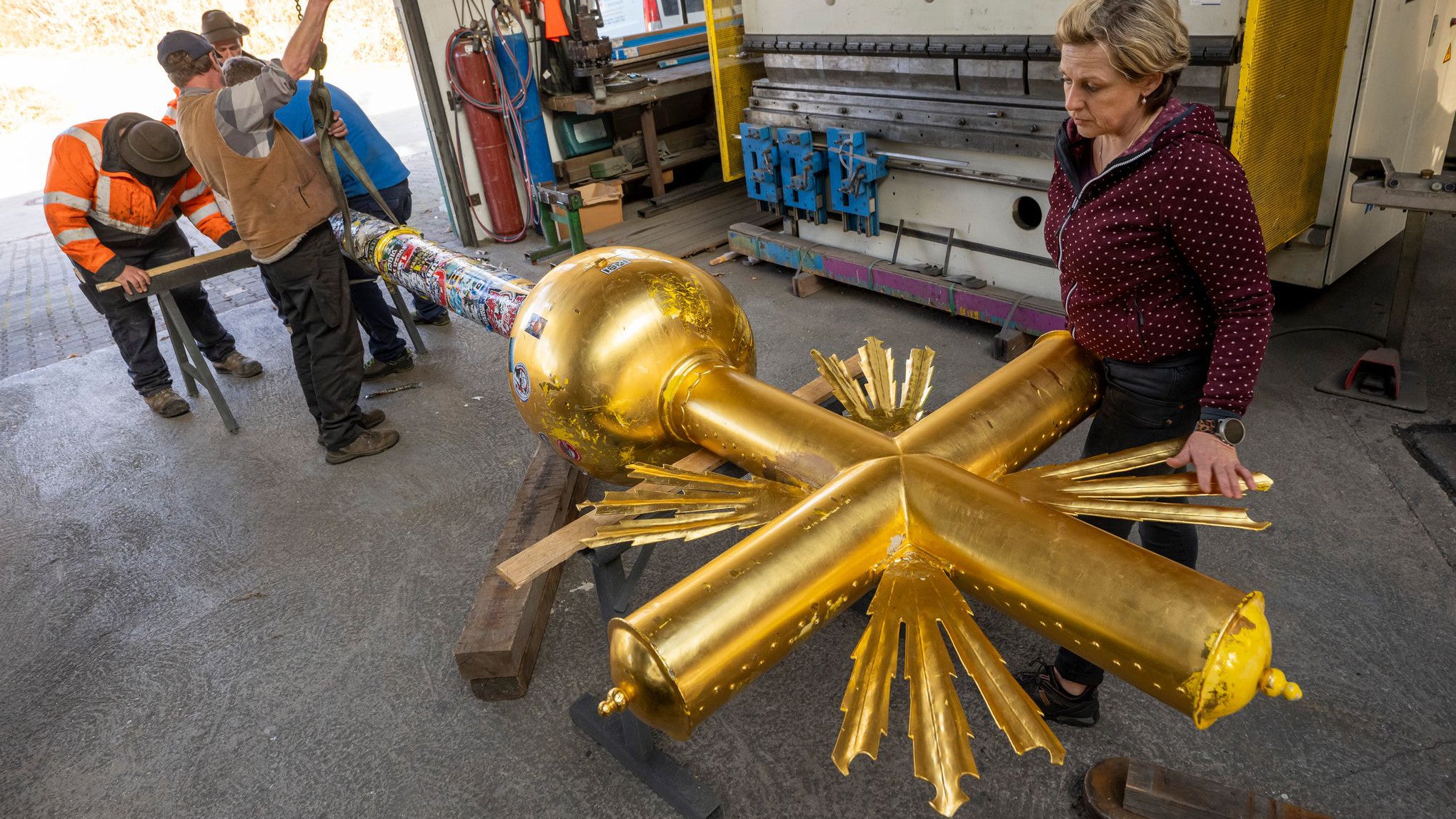 11.11.2025, Bayern, Eschenlohe: Das Zugspitz-Gipfelkreuz wird zum Kunstschmiede-Betrieb Franz W&uuml;rzinger transportiert, um dort von Andrea W&uuml;rzinger (r) restauriert zu werden. Zum Winter-Saisonstart auf der Zugspitze am 28. November soll das Kreuz wieder an seinem Platz auf dem Gipfel sein. (Peter Kneffel/dpa)