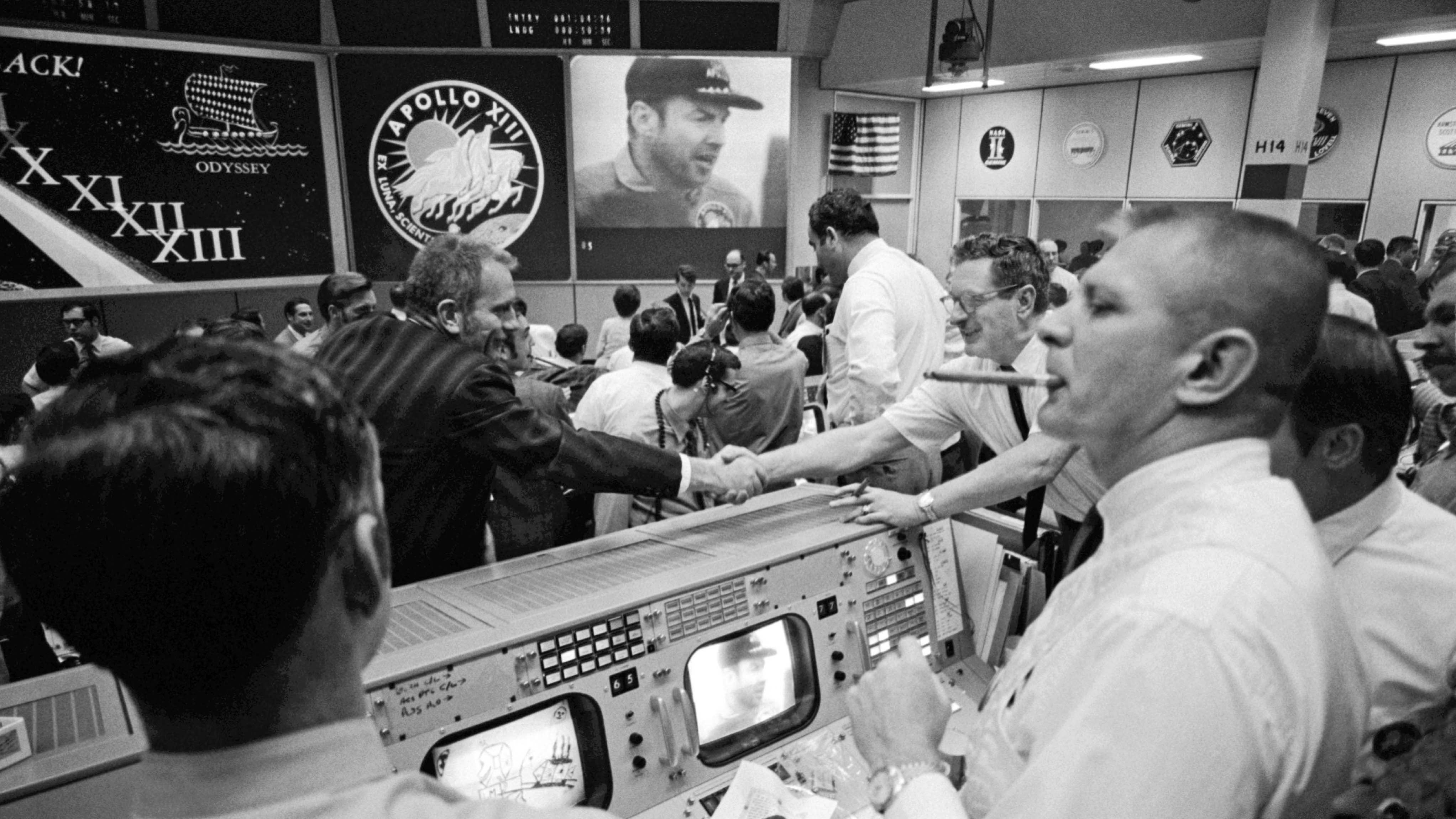 HANDOUT - 02.04.2020, USA, Houston: Deke Slayton (im schwarzen Hemd, links von der Mitte), Direktor der Flugbesatzung, und Chester M. Lee geben sich in der Mission Control die Hand, w&auml;hrend Rocco Petrone den Apollo-13-Kommandeur Jim Lovell auf dem Bildschirm beobachtet. (Bestm&ouml;gliche Bildqualit&auml;t und nur S/W) (zu dpa &laquo;&laquo;Erfolgreiches Scheitern&raquo;: Das Drama der &laquo;Apollo 13&raquo; vor 50 Jahren&raquo;) Foto: NASA/dpa - ACHTUNG: Nur zur redaktionellen Verwendung und nur mit vollst&auml;ndiger Nennung des vorstehenden Credits +++ dpa-Bildfunk +++
