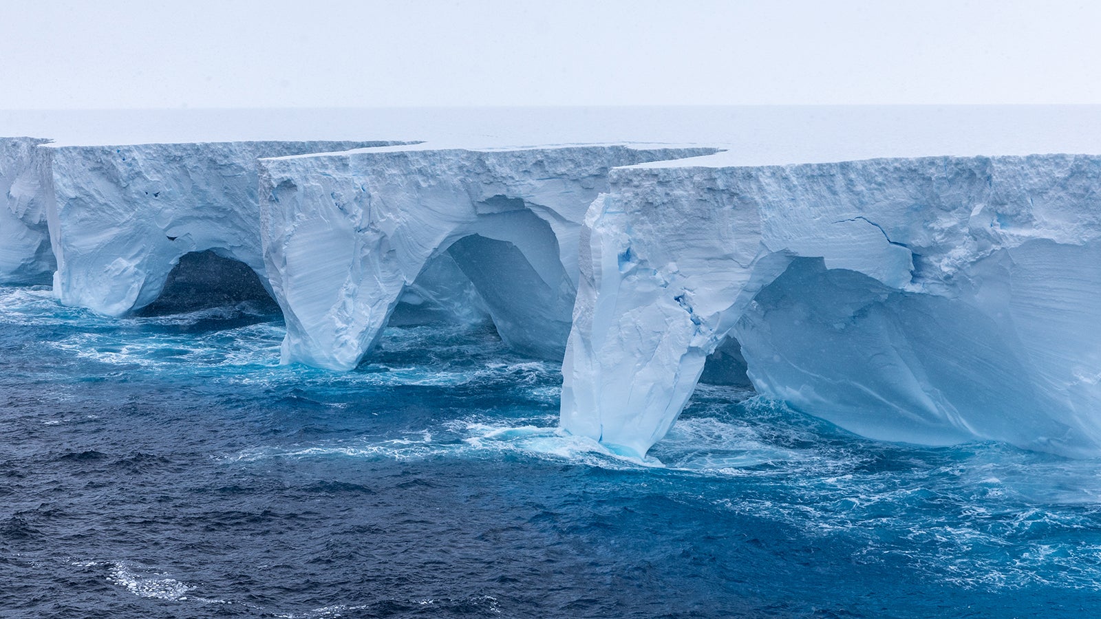 Das Bild zeigt die im Eisberg A23a gebildeten B&ouml;gen. Spektakul&auml;re Bilder vom derzeit weltweit gr&ouml;&szlig;ten Eisberg zeigen, wie Erosion riesige B&ouml;gen und h&ouml;hlenartige Vertiefungen in den Koloss gemei&szlig;elt hat.