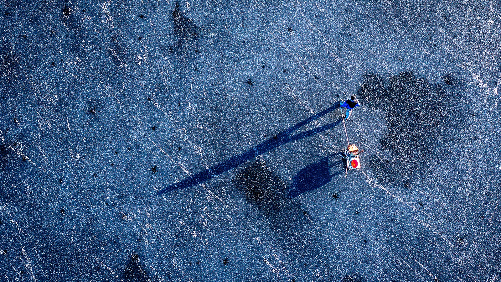 Ein Eisangler ist mit einem Schlitten auf dem zugefrorenen Vietl&uuml;bber See unterwegs. Mit frostigen Temperaturen und viel Sonnenschein zeigt sich das Winterwetter im Norden und Osten vielerorts von seiner freundlichen Seite. Foto: Jens B&uuml;ttner/dpa 