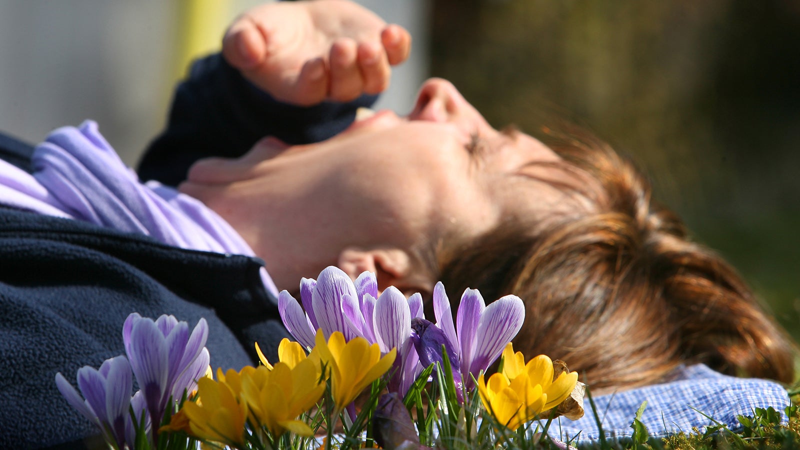 Eine Frau liegt bei W&uuml;rzburg (Bayern) auf einer mit Krokussen bewachsenen Wiese und g&auml;hnt. Die allj&auml;hrliche Fr&uuml;hjahrsm&uuml;digkeit bringt die "Zeit des gro&szlig;en G&auml;hnens" mit sich. Rund 54 Prozent der M&auml;nner und gut 60 Prozent der Frauen klagen &uuml;ber Schlappheit, Unlustgef&uuml;hl, M&uuml;digkeit, Energiemangel und Kopfschmerzen. Foto: Karl-Josef Hildenbrand/dpa 