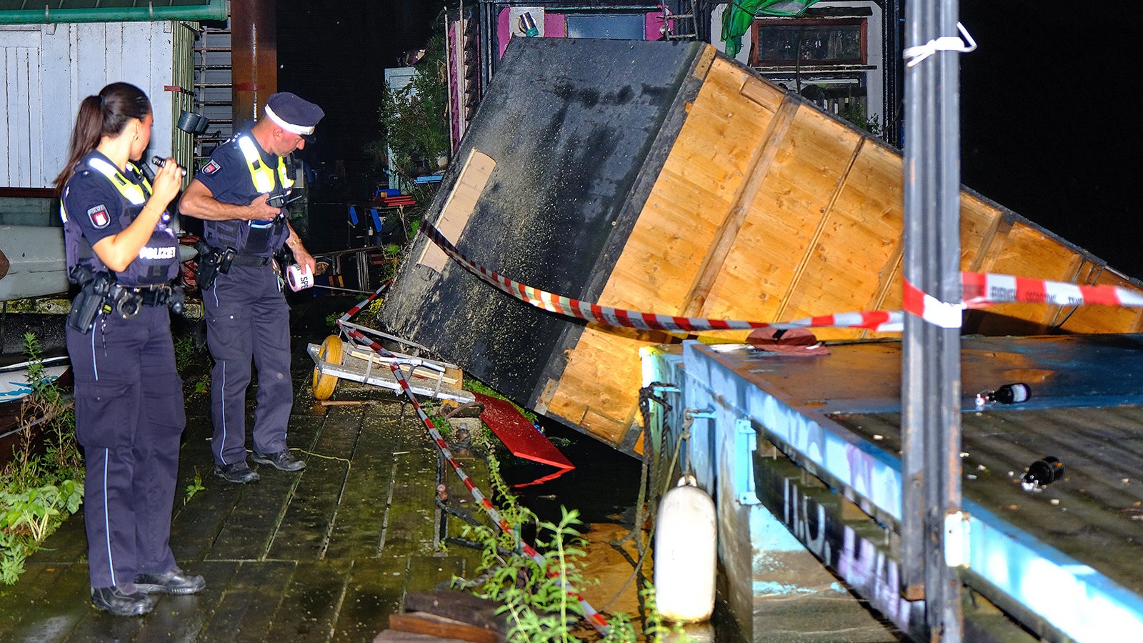 Polizisten stehen am Mittwochabend am Einsatzort in Hamburg Moorfleet am Holzhafen, nachdem eine Hausbooth&uuml;tte von Schwimmponton bei einem Gewittersturm geweht wurde. Foto: Carsten Neff/Carsten Neff / NEWS & ART/dpa +++ dpa-Bildfunk +++