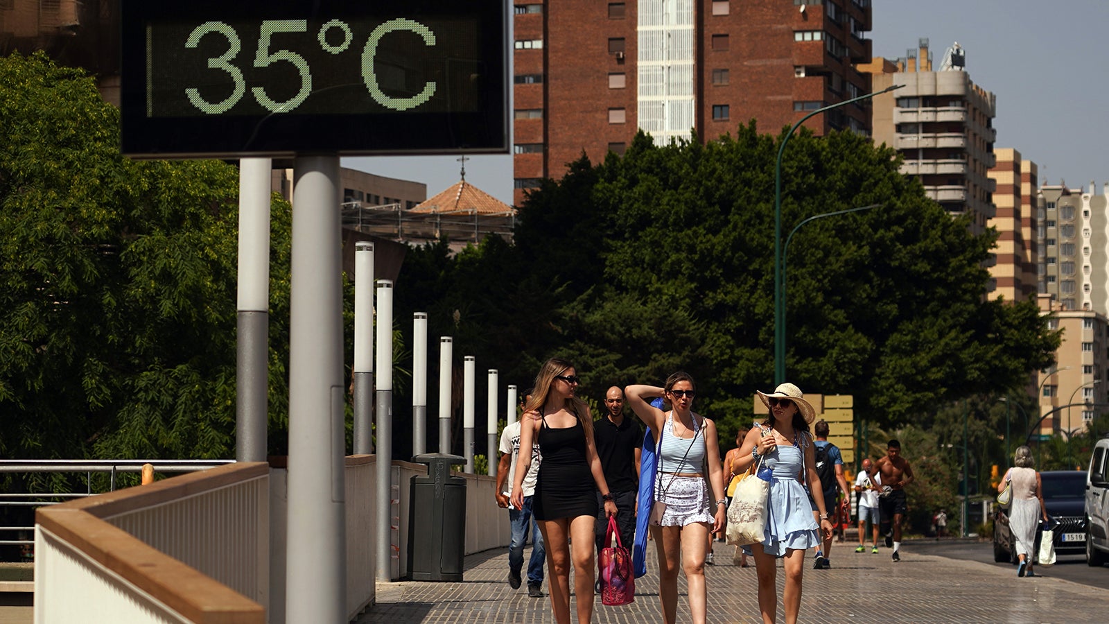 ARCHIV - 01.08.2024, Spanien, Malaga: Menschen gehen in der s&uuml;dspanischen Stadt M&aacute;laga an einem Thermometer vorbei, das 35 Grad anzeigt. (Archivbild) (zu dpa: &laquo;Berichte: Im Auto vergessenes Kind stirbt in Spanien&raquo;) Foto: &Aacute;lex Zea/EUROPA PRESS/dpa +++ dpa-Bildfunk +++