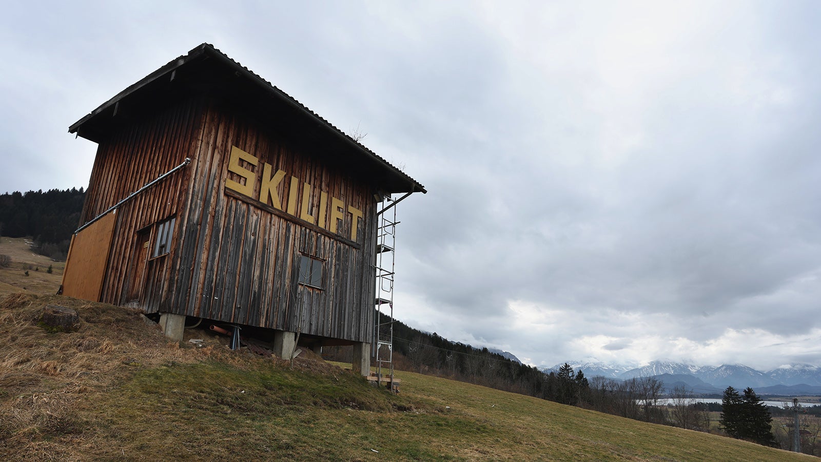 PRODUKTION - 23.02.2023, Bayern, Buching: "Skilift" ist an einer H&uuml;tte auf einer schneelosen Skipiste zu lesen. Angesichts der vielfach geringen Schneedecke in den Alpen und des regenarmen Februars droht laut Experten bald massive Trockenheit. (zu dpa: &laquo;Alarmierend wenig Schnee: Massive Trockenheit droht&raquo;) Foto: Karl-Josef Hildenbrand/dpa +++ dpa-Bildfunk +++