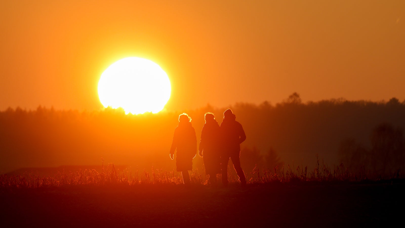 26.12.2024, Baden-W&uuml;rttemberg, Altheim: Spazierg&auml;nger laufen der untergehenden Sonne entgegen. Foto: Thomas Warnack/dpa +++ dpa-Bildfunk +++