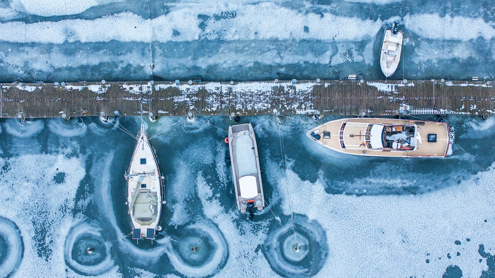 09.02.2026, Mecklenburg-Vorpommern, Kirchdorf: Boote stecken am Bootsanleger auf der Insel Poel im Eis. (Luftaufnahme mit einer Drohne) Auf dem Wasser der Ostsee hat sich vor der K&uuml;ste von Mecklenburg-Vorpommern eine dicke Eisdecke gebildet. Mit Temperaturen um die null Grad, leichtem Niederschlag und stark bew&ouml;lkt zeigt sich das Winterwetter in Norddeutschland derzeit von seiner unfreundlichen Seite. Foto: Jens B&uuml;ttner/dpa +++ dpa-Bildfunk +++