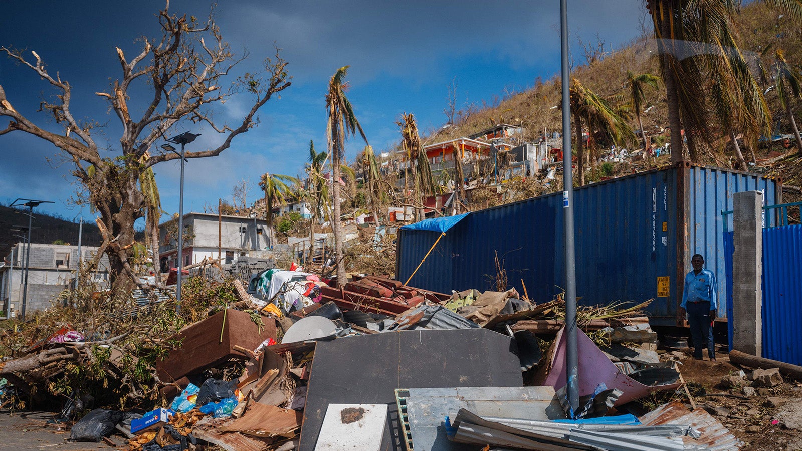 17.12.2024, Frankreich, Pamandzi: Ein Mann steht neben Tr&uuml;mmern in Pamandzi auf dem franz&ouml;sischen Territorium Mayotte im Indischen Ozean, nachdem der Zyklon Chido die Inselgruppe getroffen hatte. Nach dem verheerenden Zyklon Chido, der &uuml;ber das franz&ouml;sische Territorium Mayotte im Indischen Ozean hinwegfegte und H&auml;user auf den Inseln zerst&ouml;rte, k&auml;mpfen die Rettungskr&auml;fte gegen die Zeit an, um &Uuml;berlebende zu erreichen und dringende Hilfe zu leisten. Foto: Dimitar Dilkoff/AFP/dpa +++ dpa-Bildfunk +++