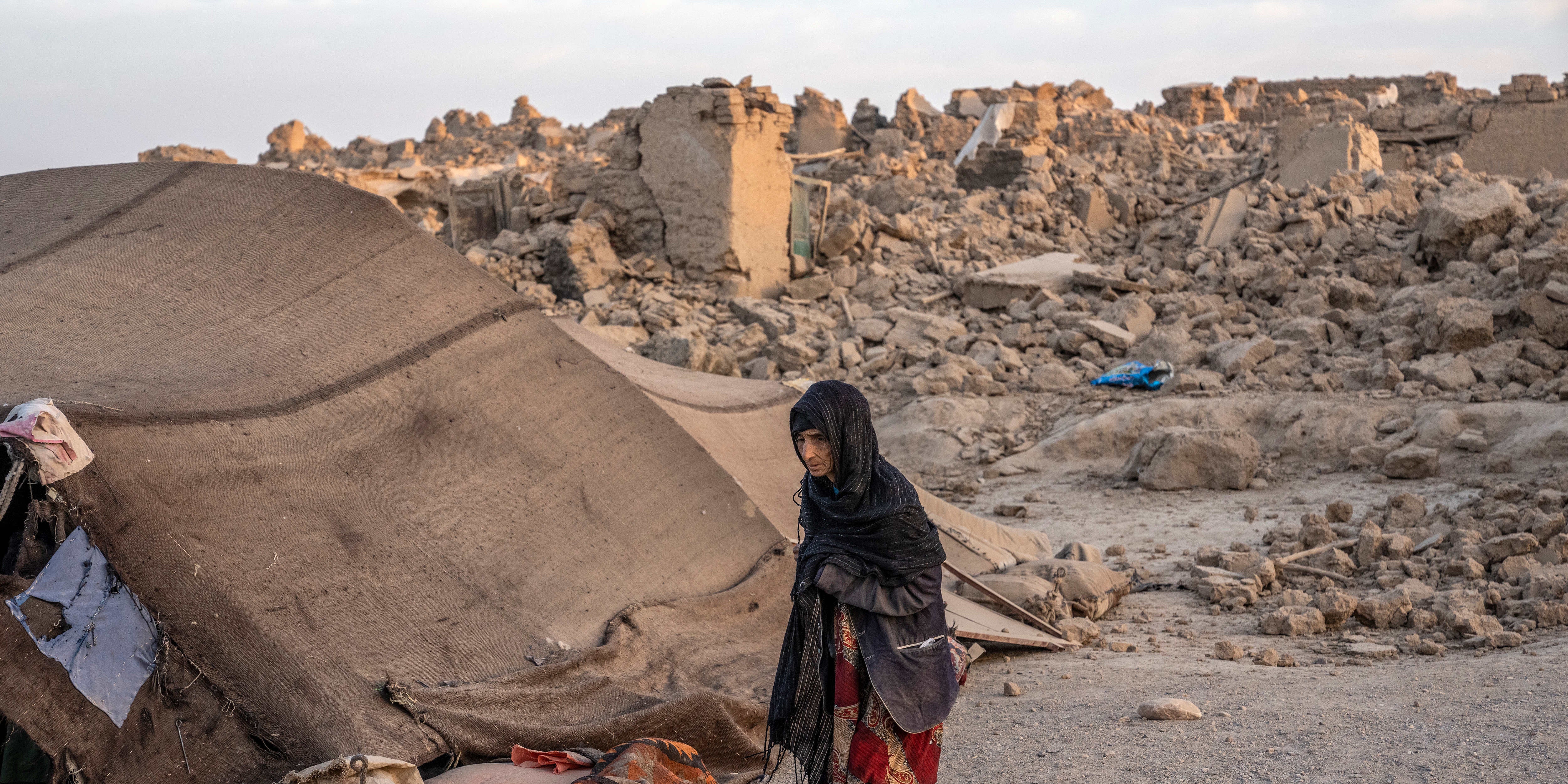 11.10.2023, Afghanistan, Herat: Eine afghanische Frau geht vor ihrem Haus, das durch das Erdbeben im Bezirk Zenda Jan zerst&ouml;rt wurde. Ein weiteres starkes Erdbeben ersch&uuml;tterte den Westen Afghanistans. Foto: Ebrahim Noroozi/AP/dpa +++ dpa-Bildfunk +++