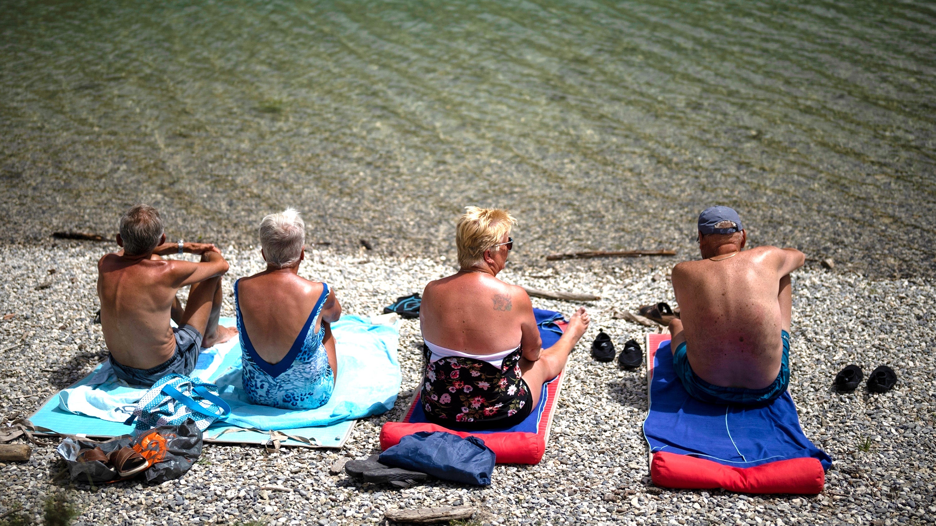 Dutch tourists sunbathe at the Lac de Castillon in southern France, Tuesday, June 20, 2023. Human-caused climate change is lengthening droughts in southern France, meaning the reservoirs are increasingly drained to lower levels to maintain the power generation and water supply needed for nearby towns and cities. (AP Photo/Daniel Cole)