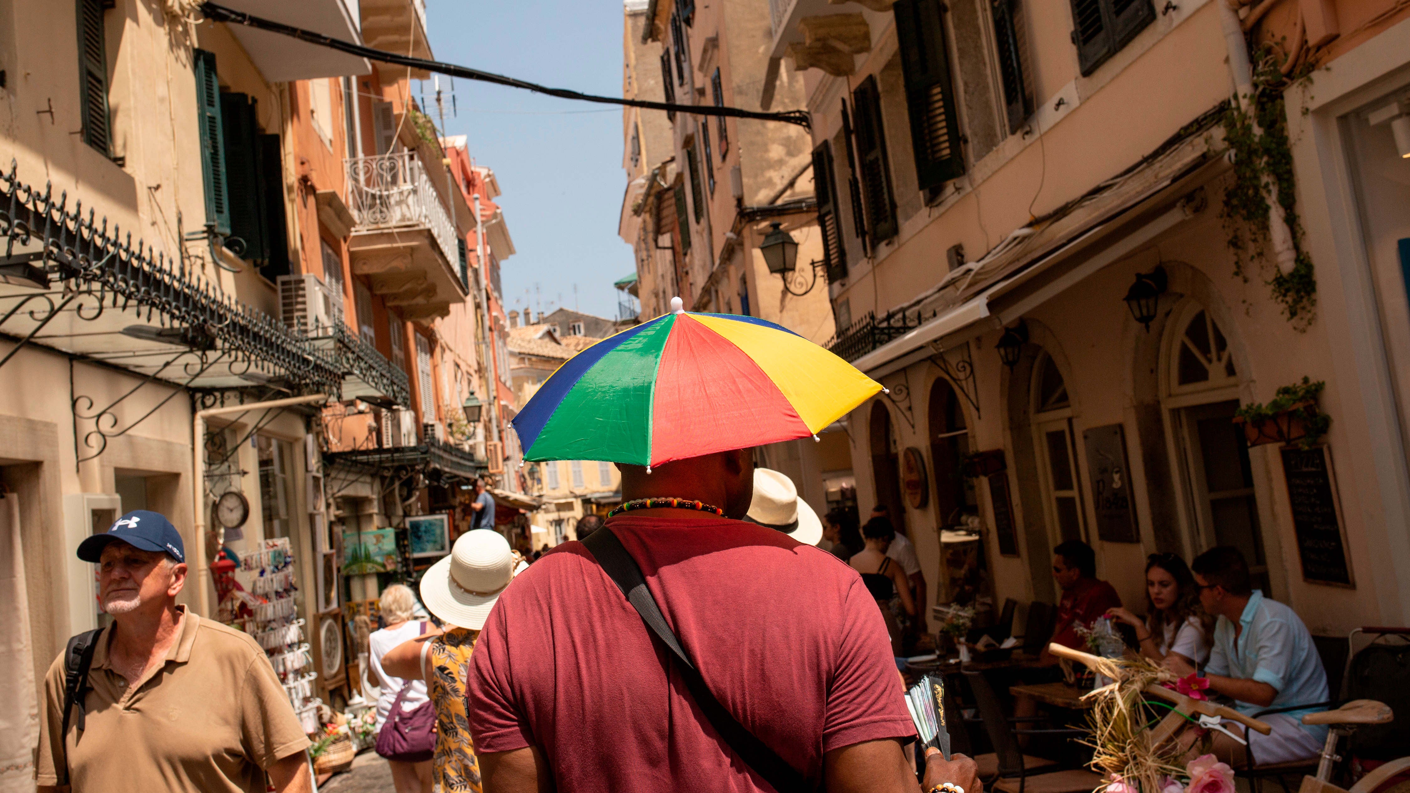 14.07.2023, Griechenland, Korfu-Stadt: Ein Mann sch&uuml;tzt sich mit einem Schirmhut gegen die Sonne an diesem hei&szlig;en Tag in Korfu-Stadt auf der Insel Korfu. Hitze ohne Ende in weiten Teilen Griechenlands. Die 40-Grad-Marke wurde vielerorts &uuml;bertroffen. Arch&auml;ologische St&auml;tten mussten schlie&szlig;en. Und ein Ende der Hitzewelle ist nicht absehbar. Foto: Socrates Baltagiannis/dpa +++ dpa-Bildfunk +++