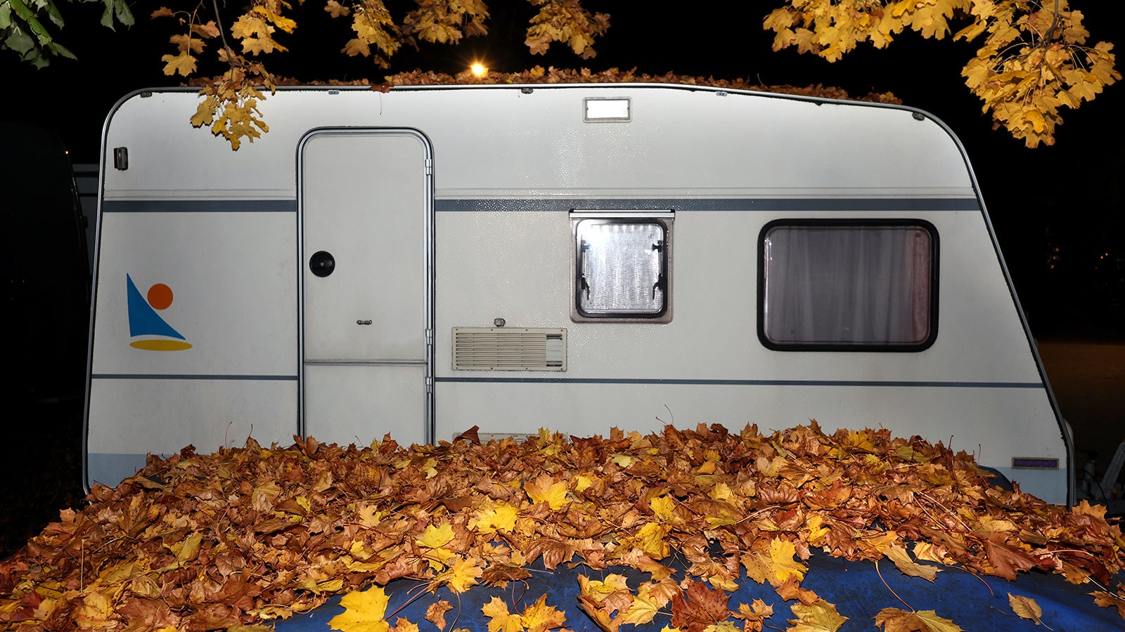 20.10.2025, Kaufbeuren: Hinter Herbstbl&auml;ttern steht am fr&uuml;hen Morgen ein auf einem Parkplatz abgestellter Wohnwagen. Foto: Karl-Josef Hildenbrand/dpa +++ dpa-Bildfunk +++