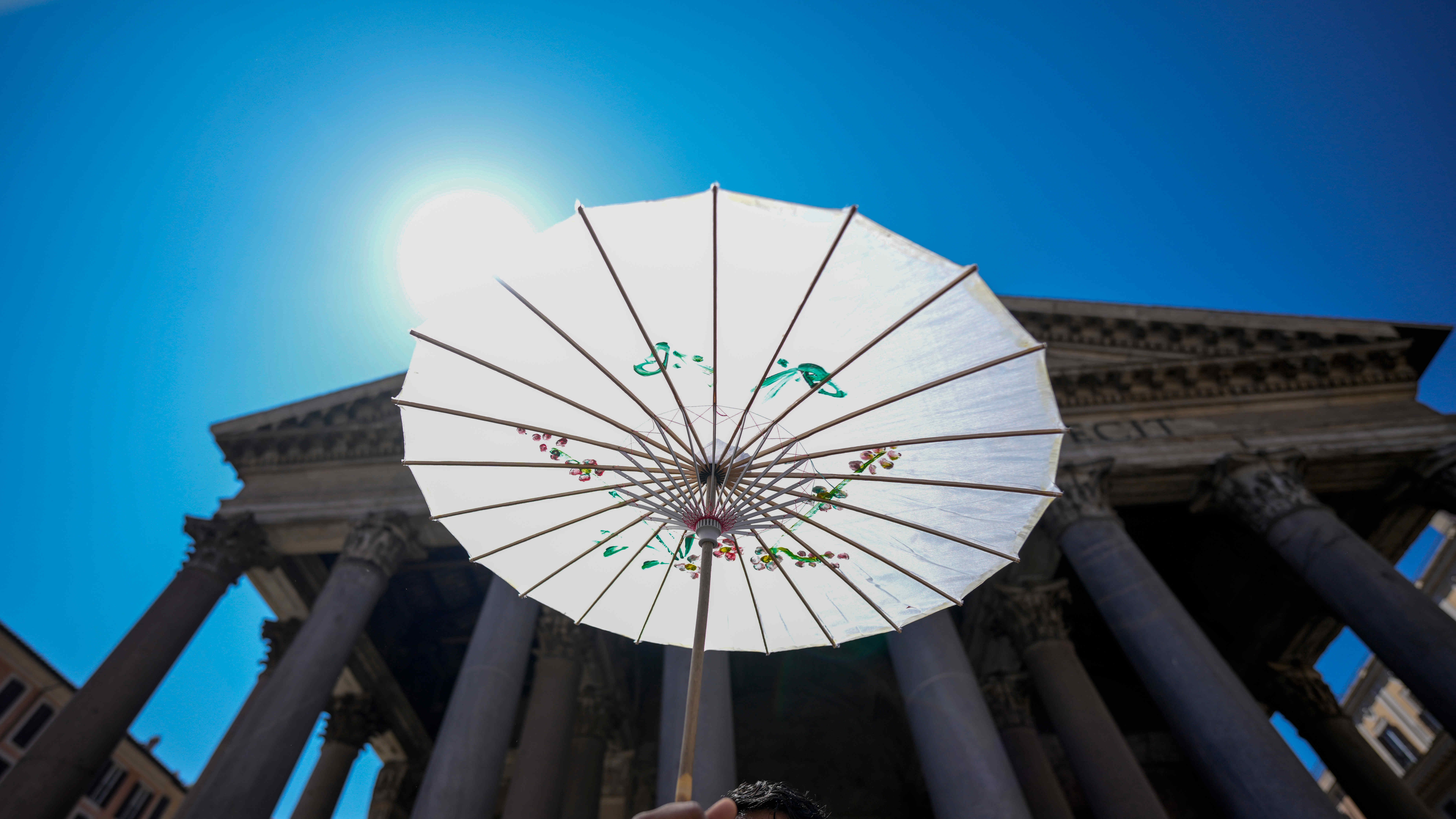 ARCHIV - 11.07.2024, Italien, Rom: Ein Mann sch&uuml;tzt sich w&auml;hrend einer Hitzewelle mit einem Papierschirm vor dem Pantheon in Rom. (zu dpa: &laquo;Hitzewelle in Italien: H&ouml;chste Warnstufe in 17 St&auml;dten&raquo;) Foto: Andrew Medichini/AP/dpa +++ dpa-Bildfunk +++