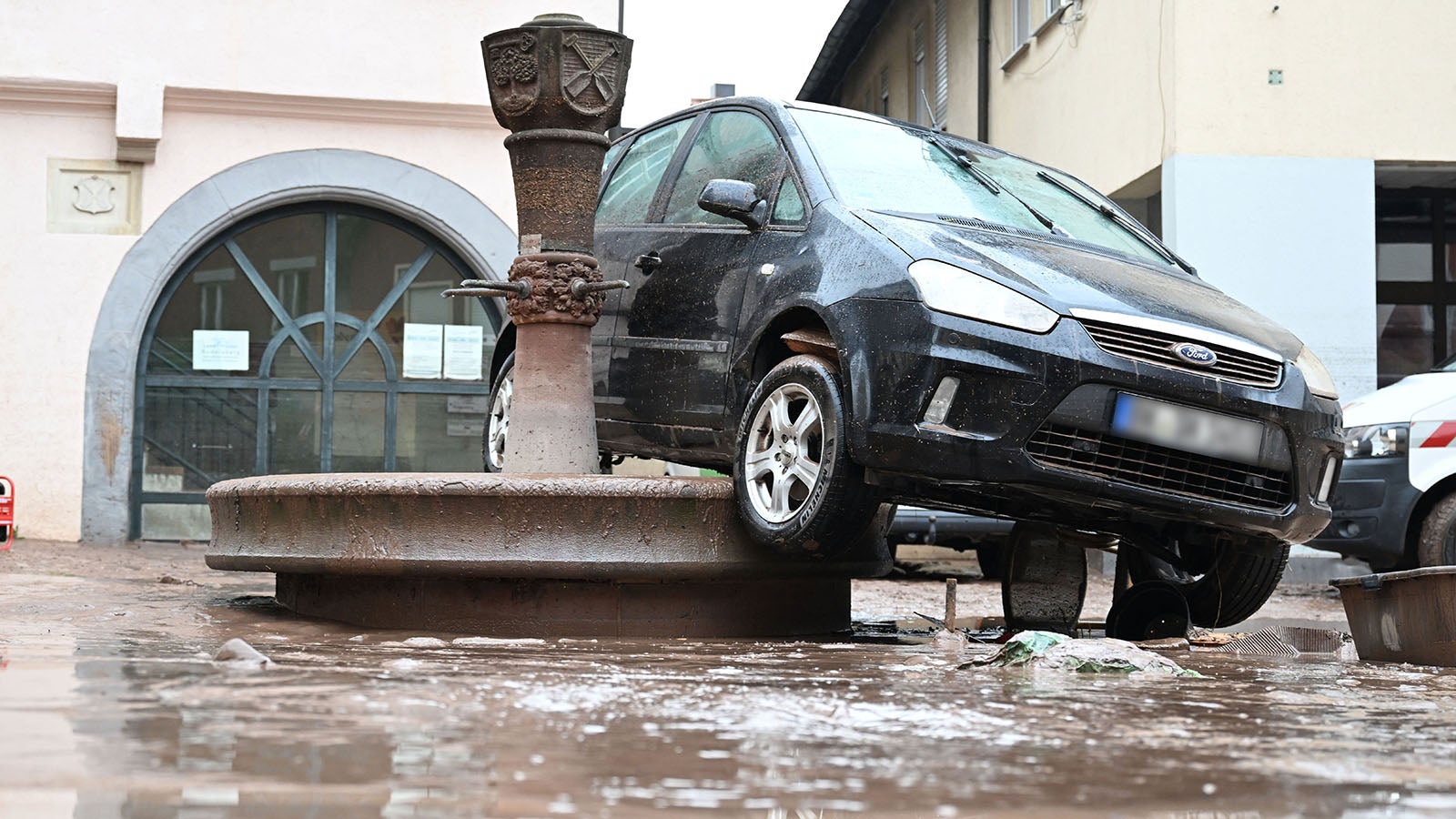 03.06.2024, Baden-W&uuml;rttemberg, Rudersberg: Auf einem Brunnen in Rudersberg steht ein durch ein Hochwasser weggesp&uuml;ltes Auto. Seit Tagen k&auml;mpfen die Helfer in Bayern und Baden-W&uuml;rttemberg gegen die Flut und ihre Folgen. Die Hochwasserlage ist weiter dynamisch und un&uuml;bersichtlich. (Wiederholung mit ver&auml;ndertem Bildausschnitt) Foto: dpa +++ dpa-Bildfunk +++