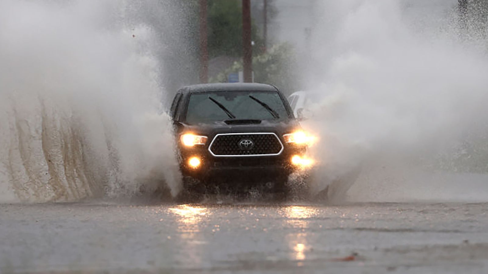 REDLANDS, CALIFORNIA - AUGUST 20: A car kicks up water as it drives on a flooded street as tropical storm Hilary approaches on August 20, 2023 in Redlands, California. Southern California is under a first-ever tropical storm warning as Hilary approaches with parts of California, Arizona and Nevada preparing for flooding and heavy rains. All California state beaches have been closed in San Diego and Orange counties in preparation for the impacts from the storm which was downgraded from hurricane status. (Photo by Justin Sullivan/Getty Images)