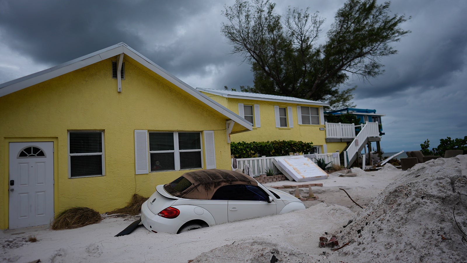 Ein Auto liegt nach Hurrikan Helene halb vergraben im Sand am Bradenton Beach. Die Aufr&auml;umarbeiten nach Hurrikan Helene sind noch nicht einmal beendet und die Menschen in Florida m&uuml;ssen erneut vor einem Hurrikan fliehenFoto: Rebecca Blackwell/AP/dpa +++ dpa-Bildfunk +++