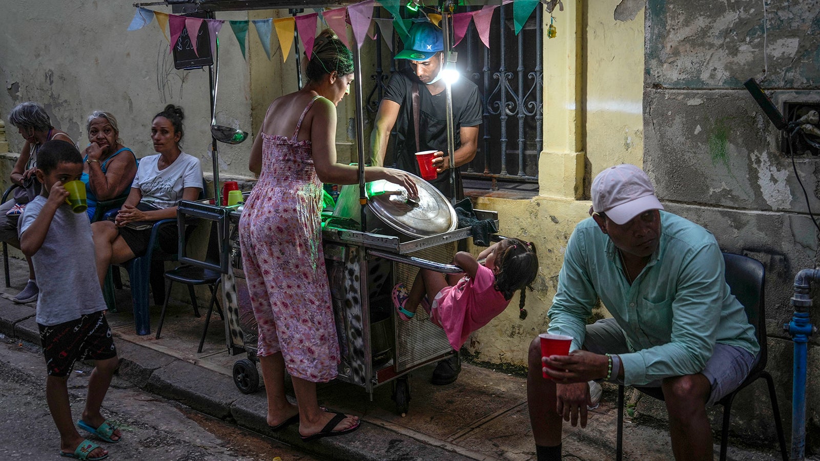 dpatopbilder - 21.10.2024, Kuba, Havanna: Eine Frau kauft Suppe von einem Stra&szlig;enh&auml;ndler. Drei Tage nach dem landesweiten Stromausfall auf Kuba haben viele Haushalte nach offiziellen Angaben wieder Elektrizit&auml;t. Foto: Ramon Espinosa/AP +++ dpa-Bildfunk +++