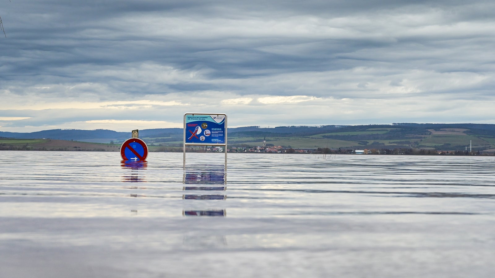 ARCHIV - 31.12.2023, Th&uuml;ringen, Kelbra: Schilder stehen im Hochwasser auf dem Campingplatz an der Talsperre Kelbra. Europa ist nach Angaben der Europ&auml;ische Umweltagentur (EEA) der Kontinent, der sich am schnellsten erw&auml;rmt. (zu dpa: &laquo;EU-Bericht sieht hohe Risiken durch Klimaerw&auml;rmung&raquo;) Foto: Heiko Rebsch/dpa +++ dpa-Bildfunk +++