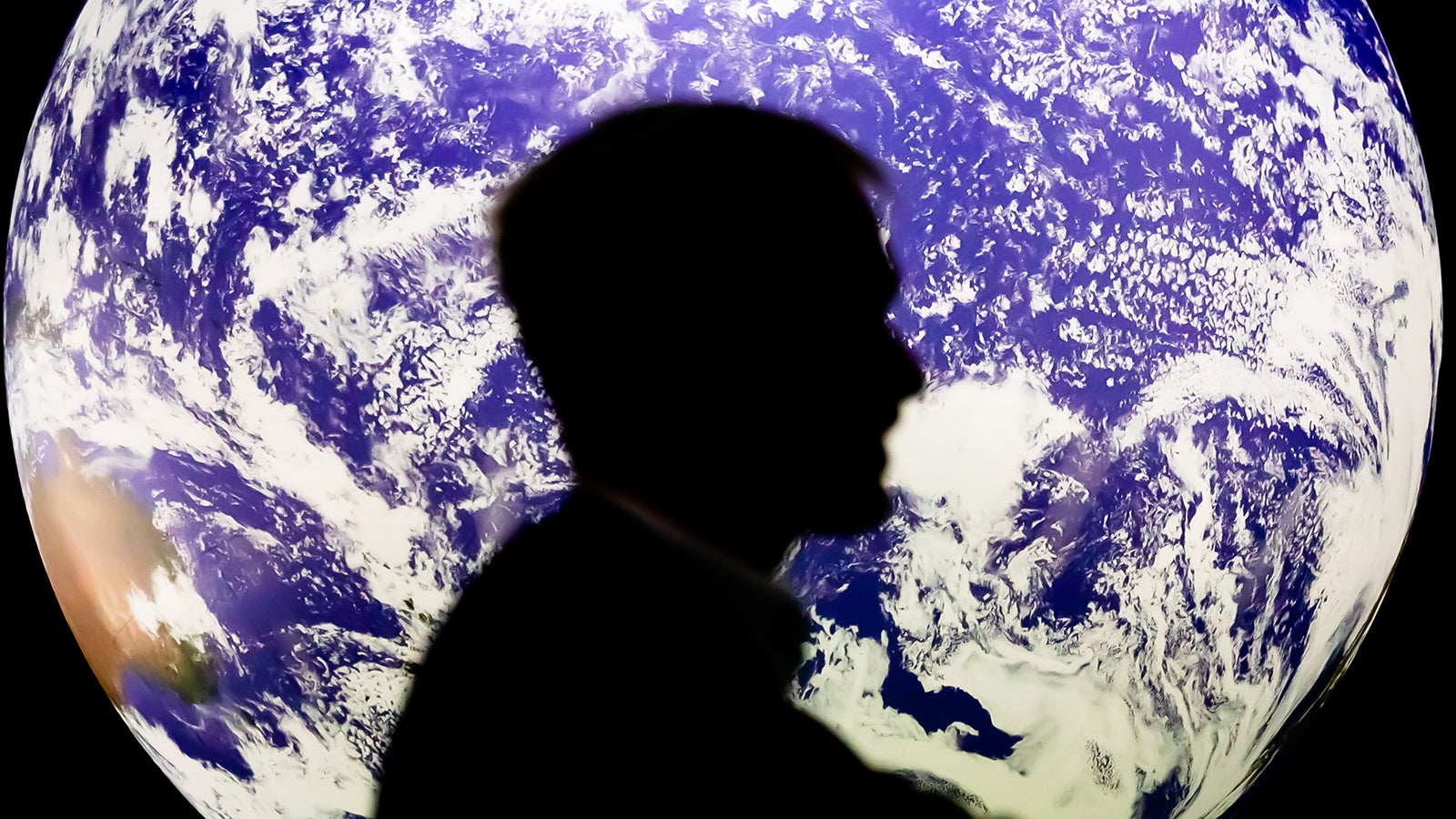 ARCHIV - 11.11.2021, Gro&szlig;britannien, Glasgow: Ein Mann sitzt bei der UN-Klimakonferenz COP26 2021 vor einem leuchtenden Globus. (zu dpa: &laquo;Report: Mensch erhitzt Erde so schnell wie nie&raquo;) Foto: Christoph Soeder/dpa +++ dpa-Bildfunk +++