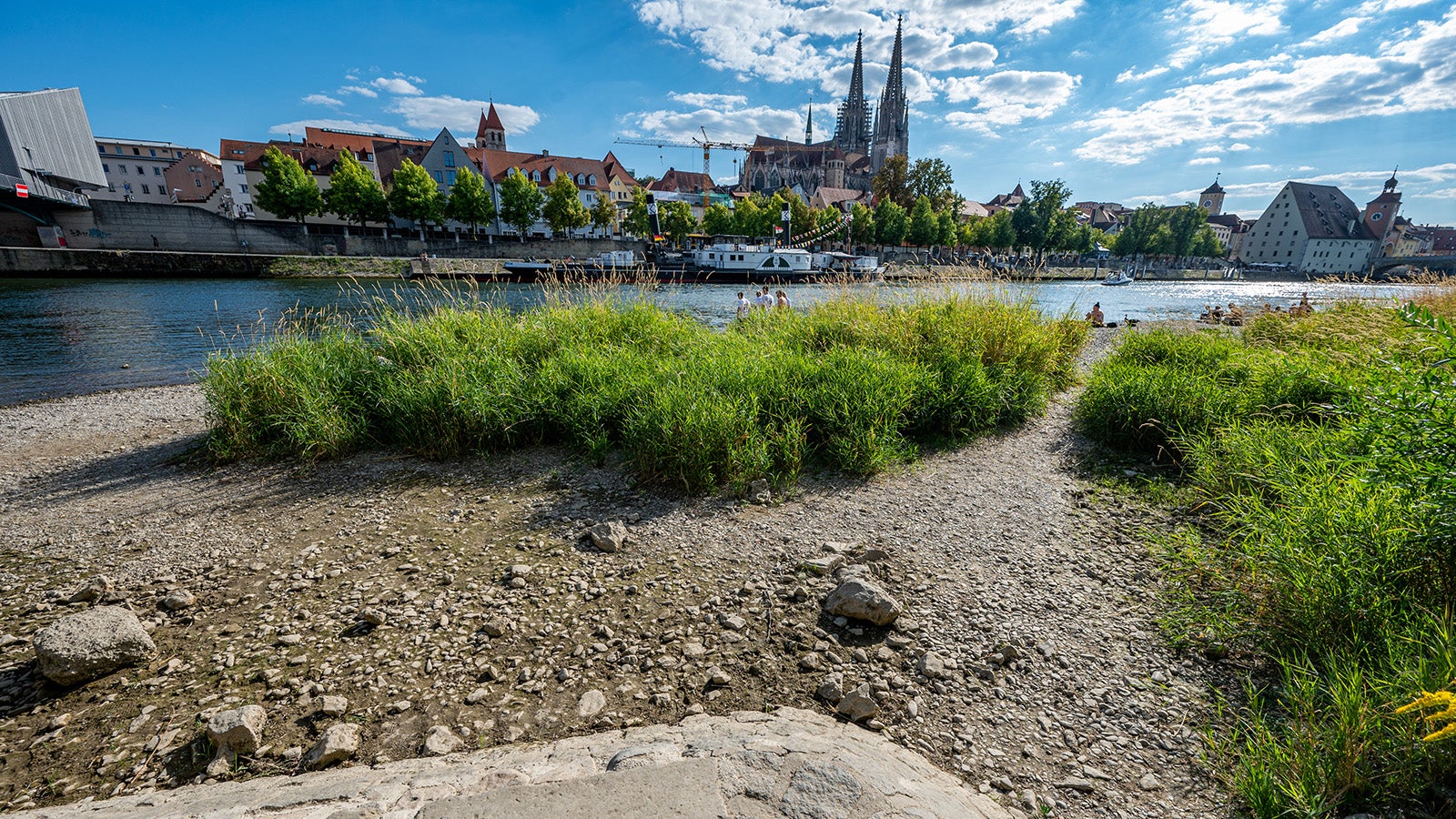 ARCHIV - 10.08.2022, Bayern, Regensburg: Niedrigwasser an der Donau in der Altstadt. Die niedrigen Wasserst&auml;nde behindern die Binnenschifffahrt in Bayern. Ob Rhein, Weser oder Donau: Die Pegelst&auml;nde mehrerer Fl&uuml;sse in Deutschland sind in diesem Jahr besonders fr&uuml;h gesunken und sehr tief. Der Klimawandel tr&auml;gt dazu bei - doch die Zusammenh&auml;nge sind vielf&auml;ltig. Besonders f&uuml;r die Wassertierwelt birgt das viele Gefahren. Experten rufen zur Vorsorge statt Nachsorge auf. Foto: Armin Weigel/dpa +++ dpa-Bildfunk +++