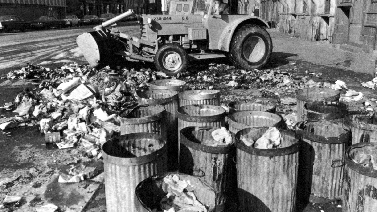 FILE - Empty garbage cans sit on a Harlem street in the Manhattan borough of New York, Feb. 11, 1968, as a sanitation worker removes the last of a mountain of refuse after a sanitation strike. (AP File Photo)