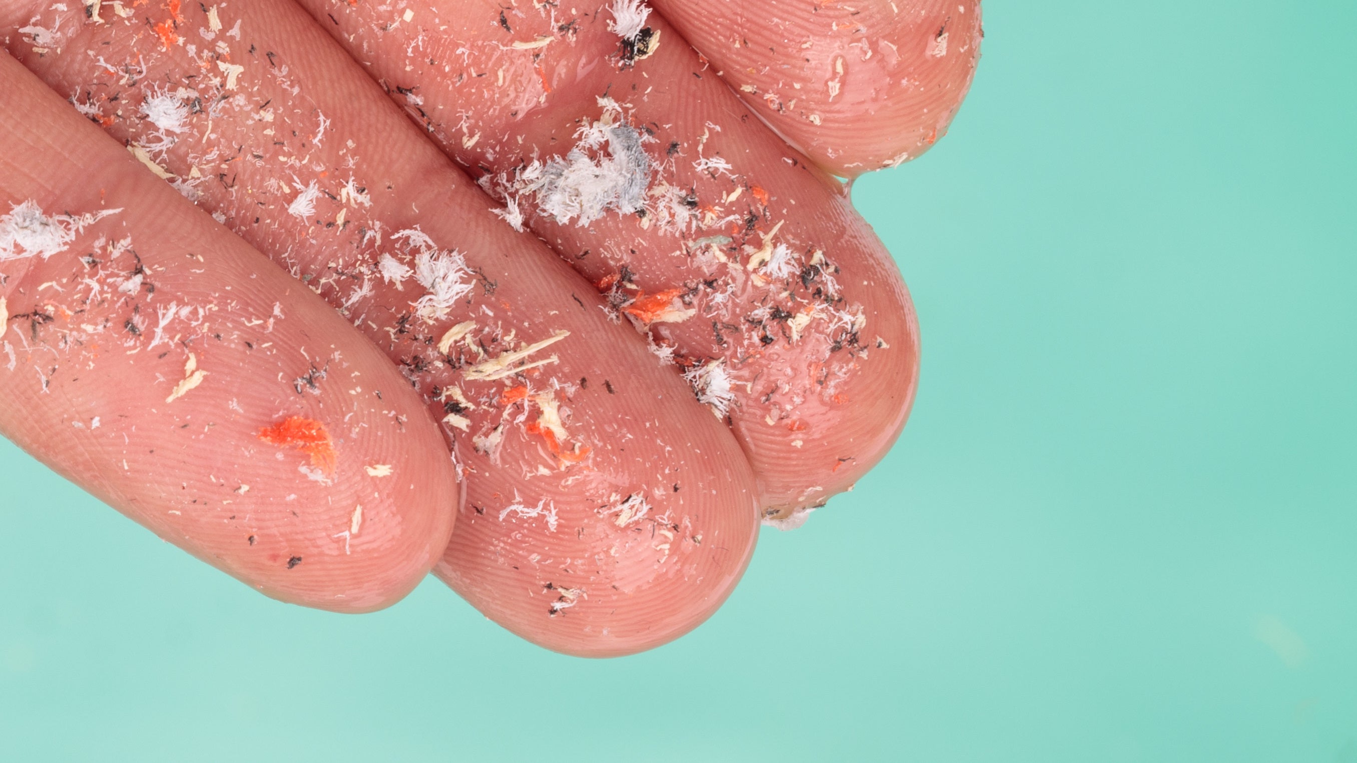 Small plastic pellets on finger. Micro plastic, problem. Close up side shot of microplastics lay on people's hands. Concept of water pollution. Idea for climate change.