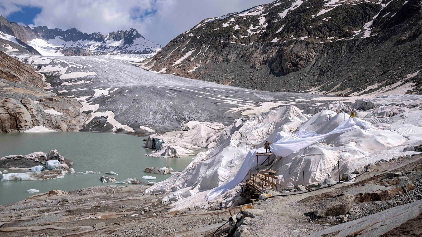 Arbeiter bereiten am Rhonegletscher in der N&auml;he von Goms Gletschermatten aus. Die Gletschermatten sind nur eine kleine L&ouml;sung, und es wird immer noch erwartet, dass die Alpengletscher bis zum Ende des Jahrhunderts verschwinden werden. Foto: Matthias Schrader/AP/dpa
